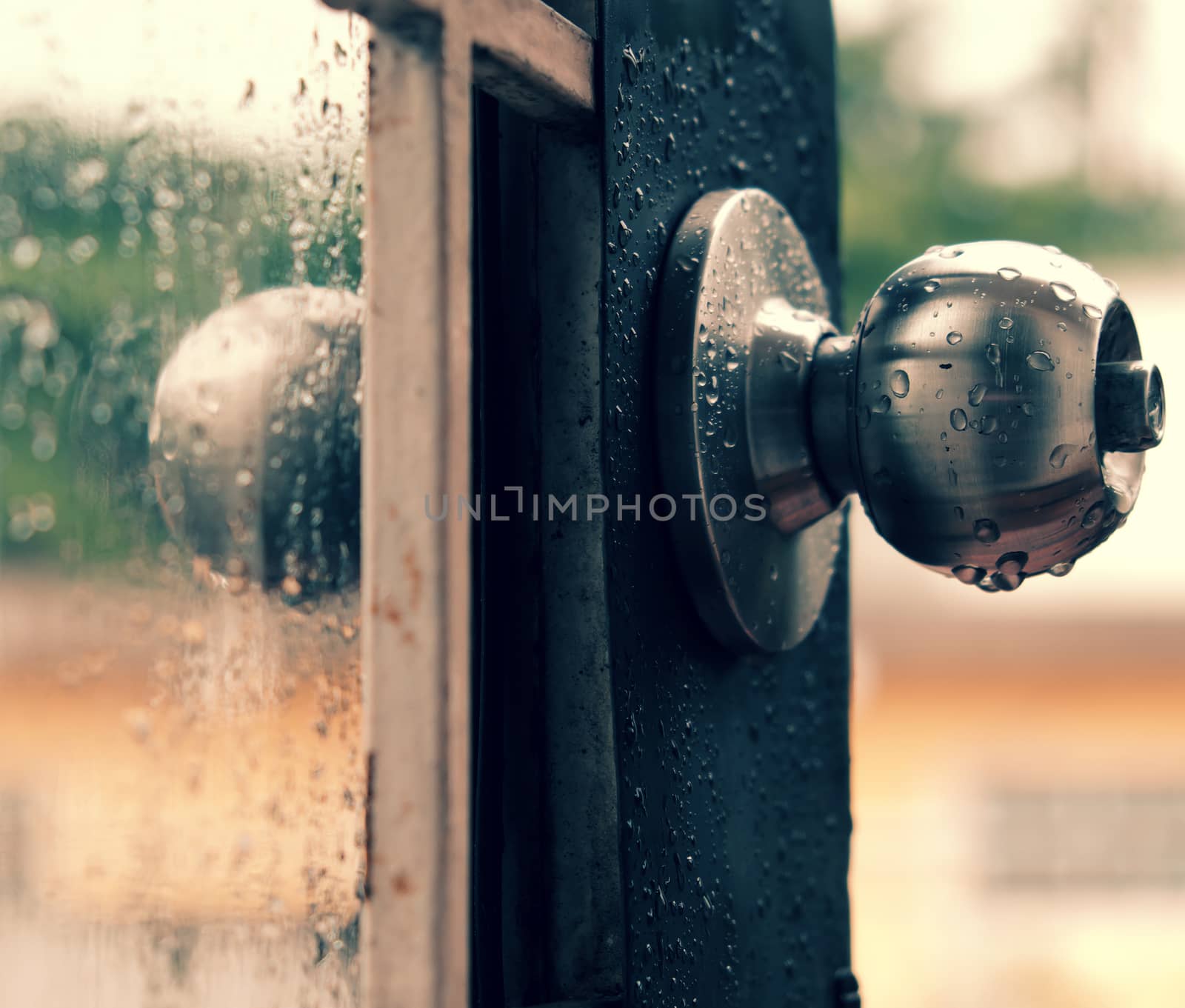 Rain drops on door handle and glass window in rainy day, drop of water falling make lonely feeling of cold day