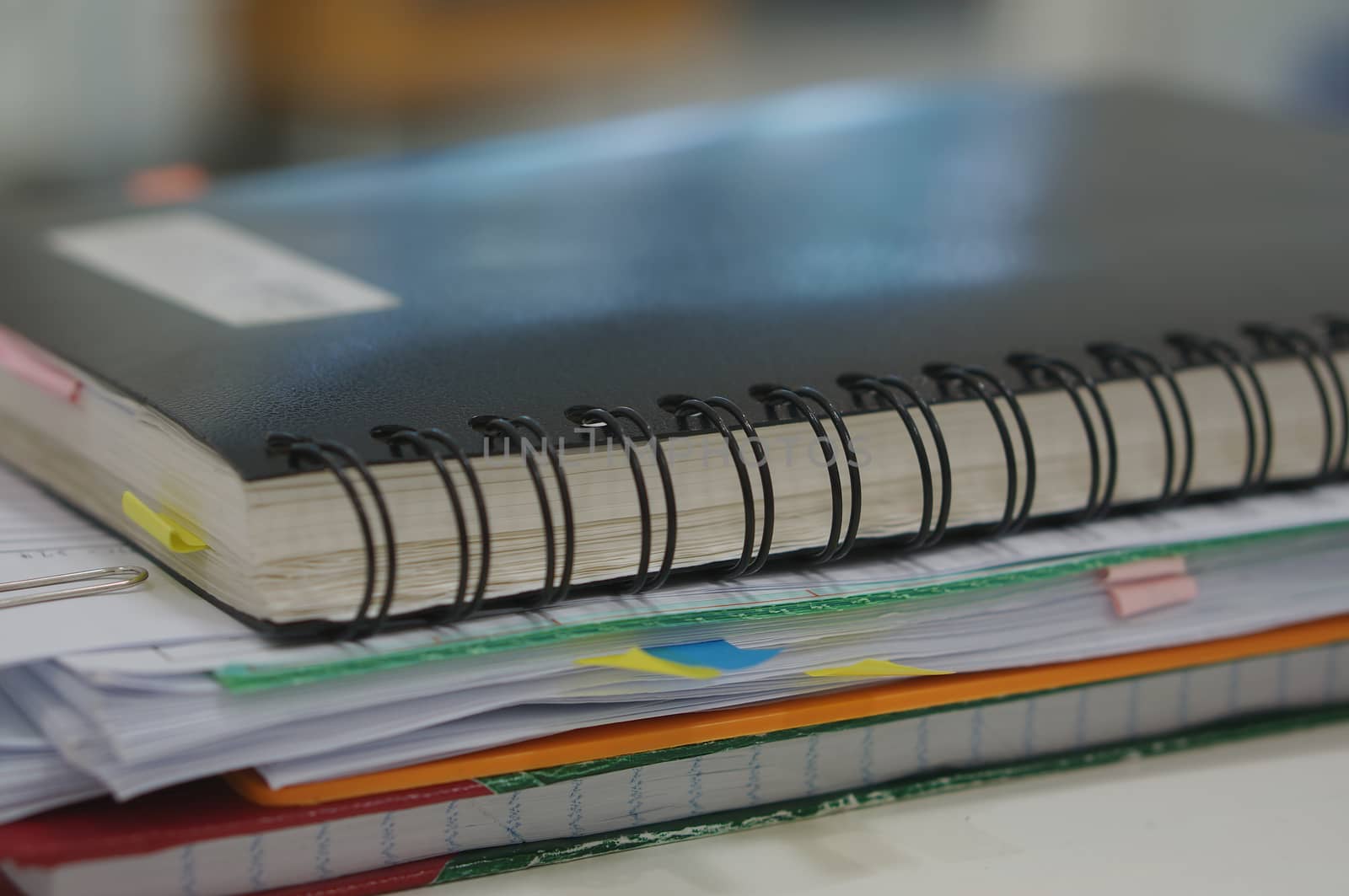 Stack of report and black notebook placed on desk at office.