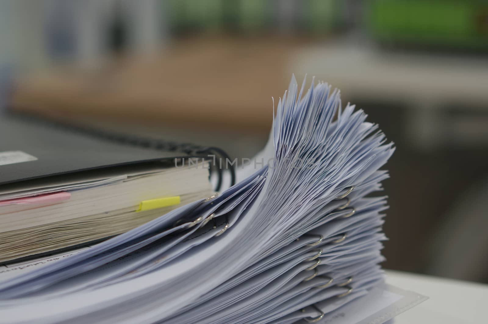 Stack of white document and black notebook on desk in office.