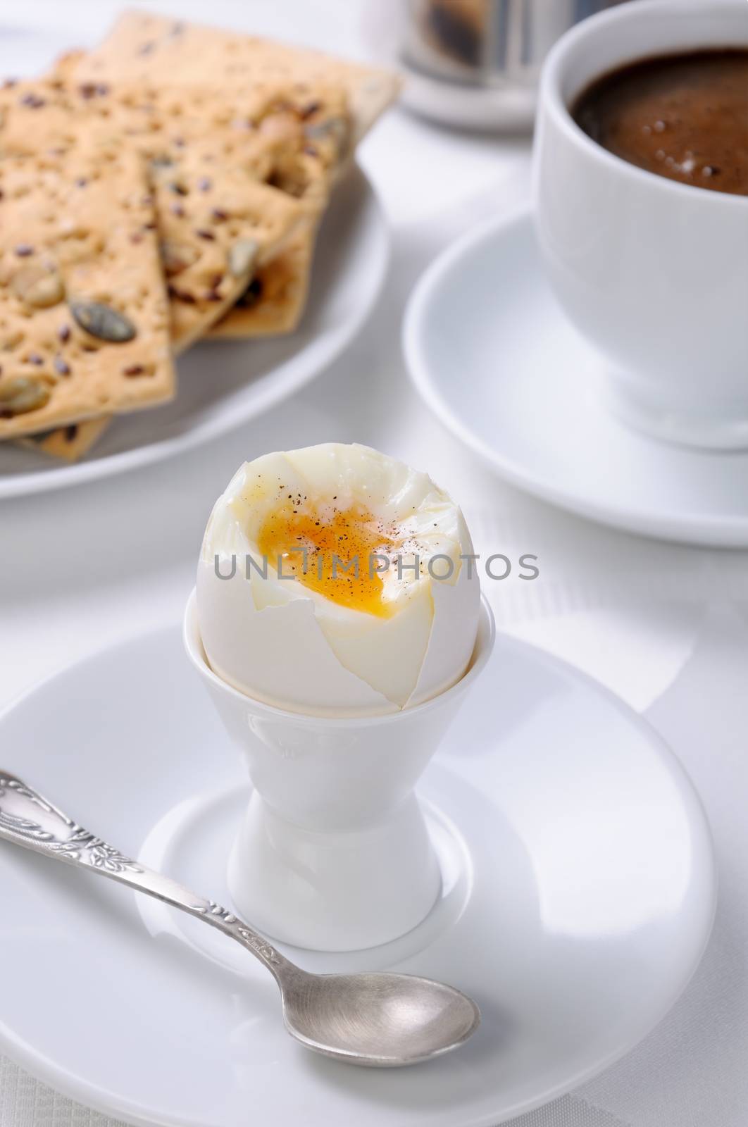 Soft-boiled egg with cup of coffee and crackers for breakfast