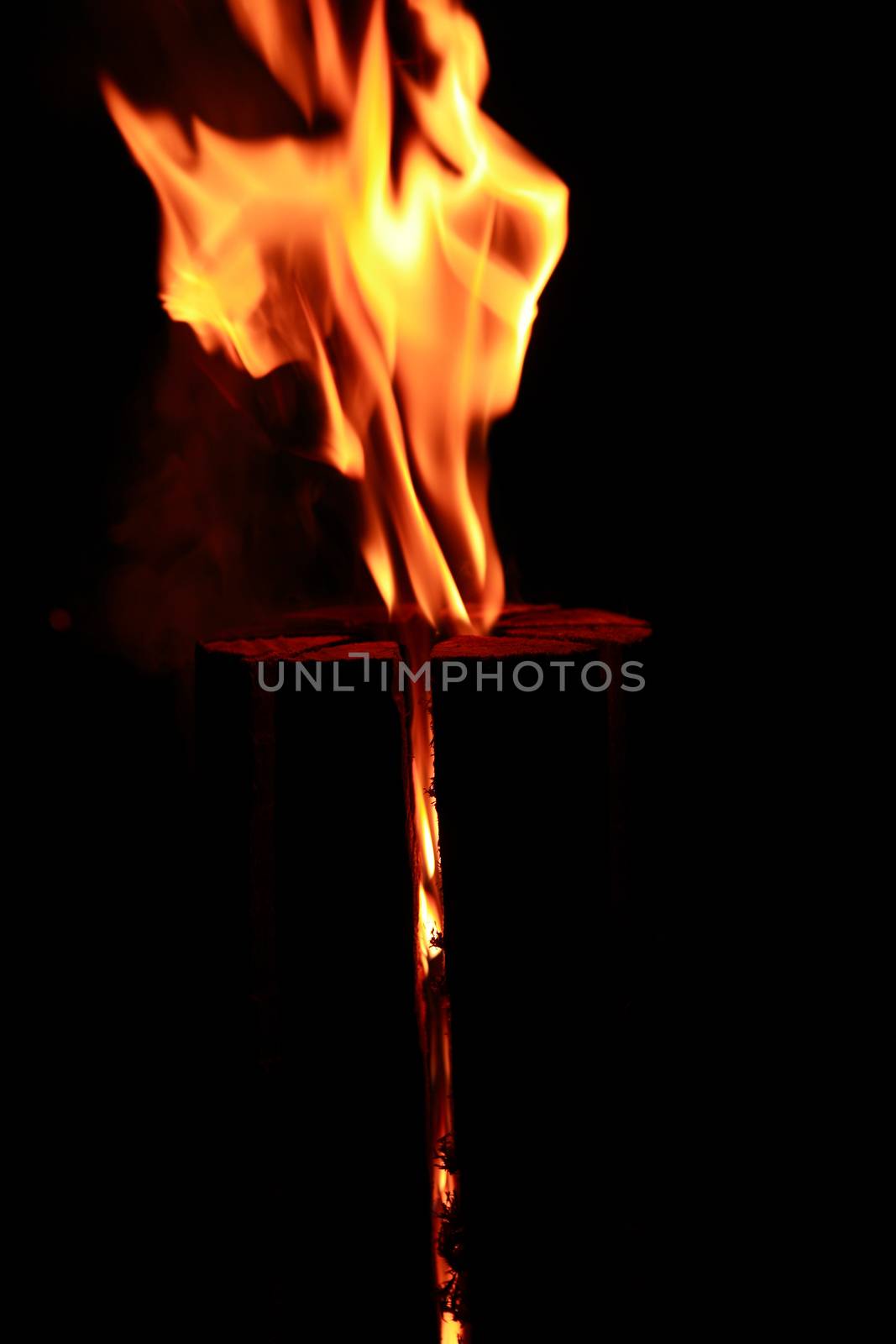 Fire flame abstract. Burning log closeup on dark background