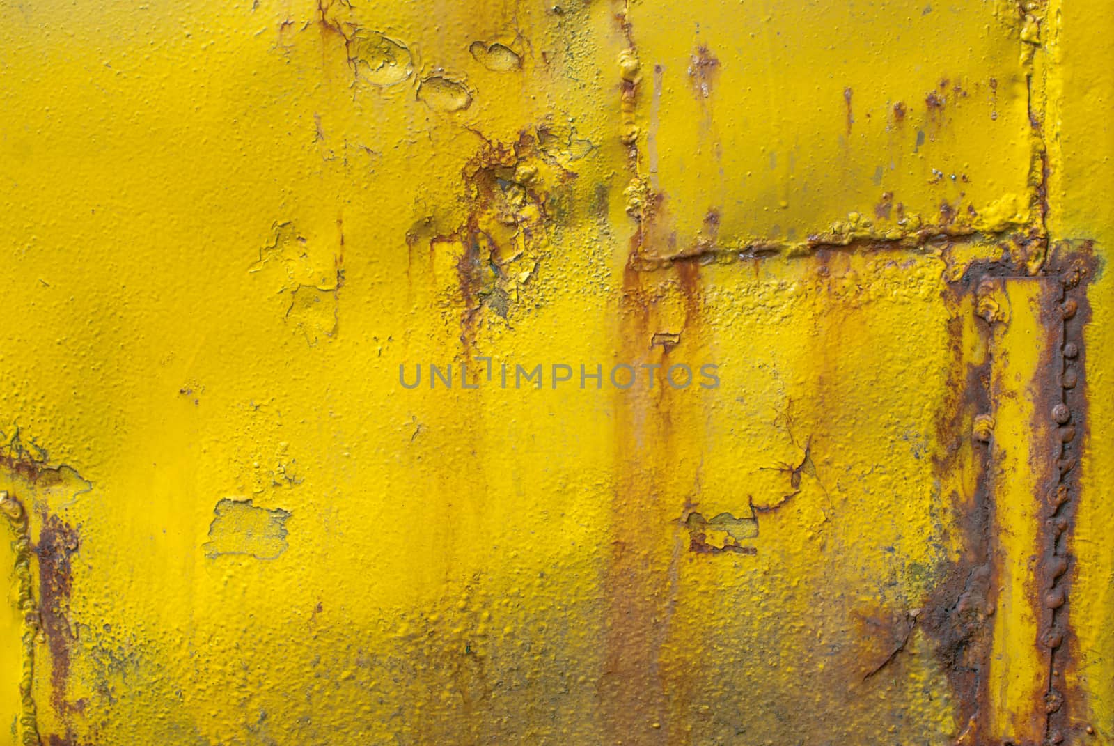 fragment of an iron surface is covered with yellow color paint, which has long been under the influence of different climatic conditions