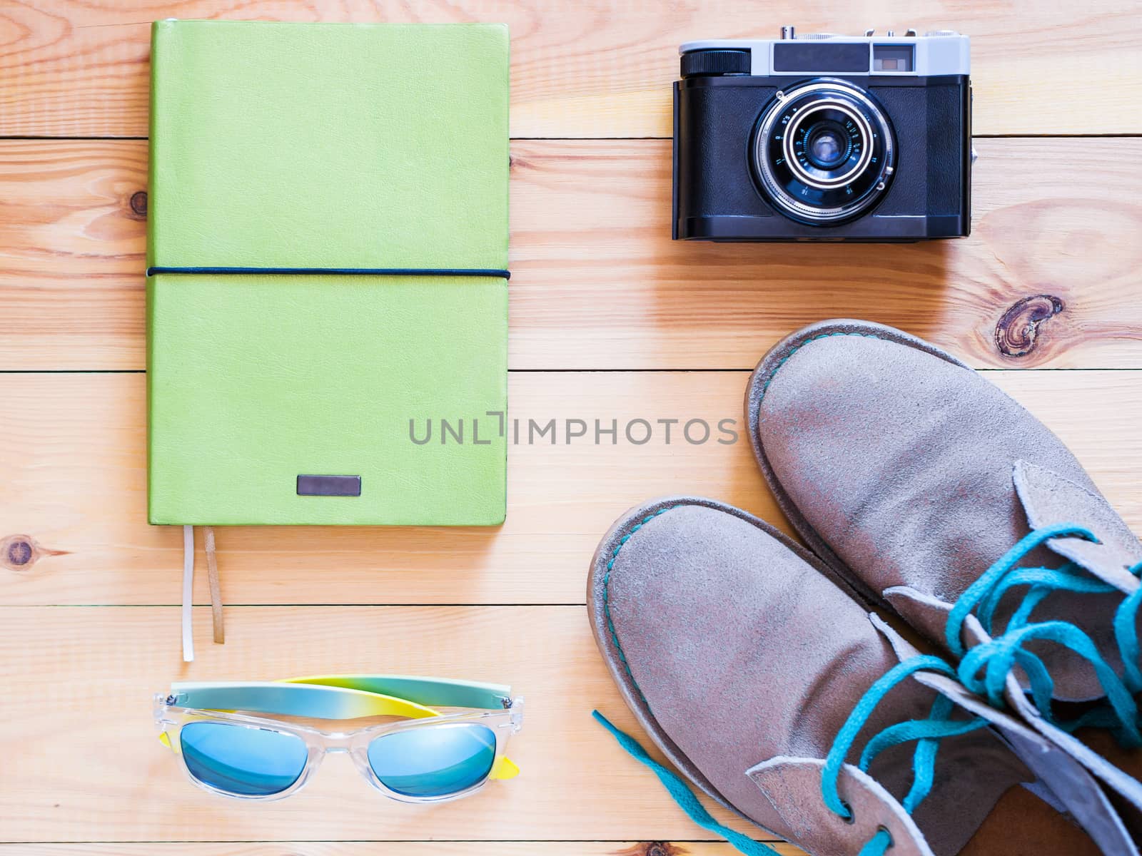 Set of travel and resort stuff. Old 35 mm camera, note book, sunglasses and desert boots on wooden table. Top view, flat lay