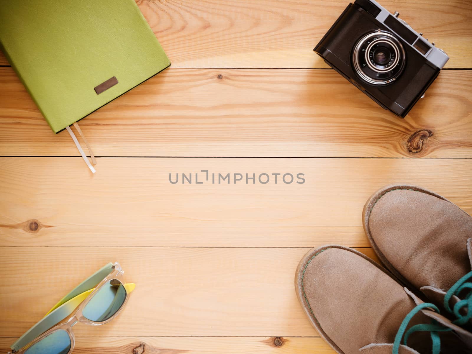 Set of travel and resort stuff. Old 35mm camera, note book, sunglasses and desert boots on wooden table. Top view, flat lay with copy space