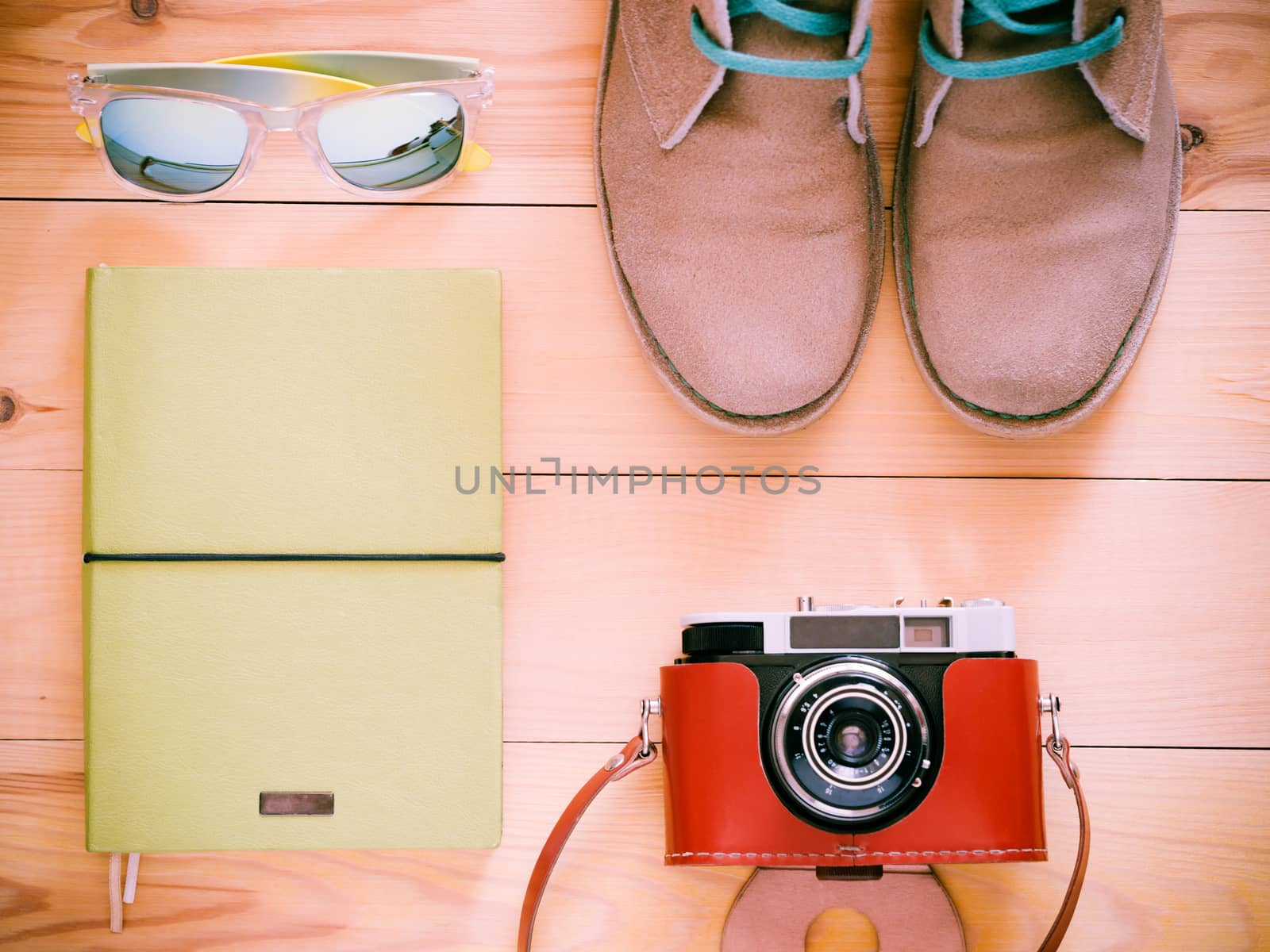 Set of travel and resort stuff. Old 35 mm camera, note book, sunglasses and desert boots on wooden table. Top view, flat lay