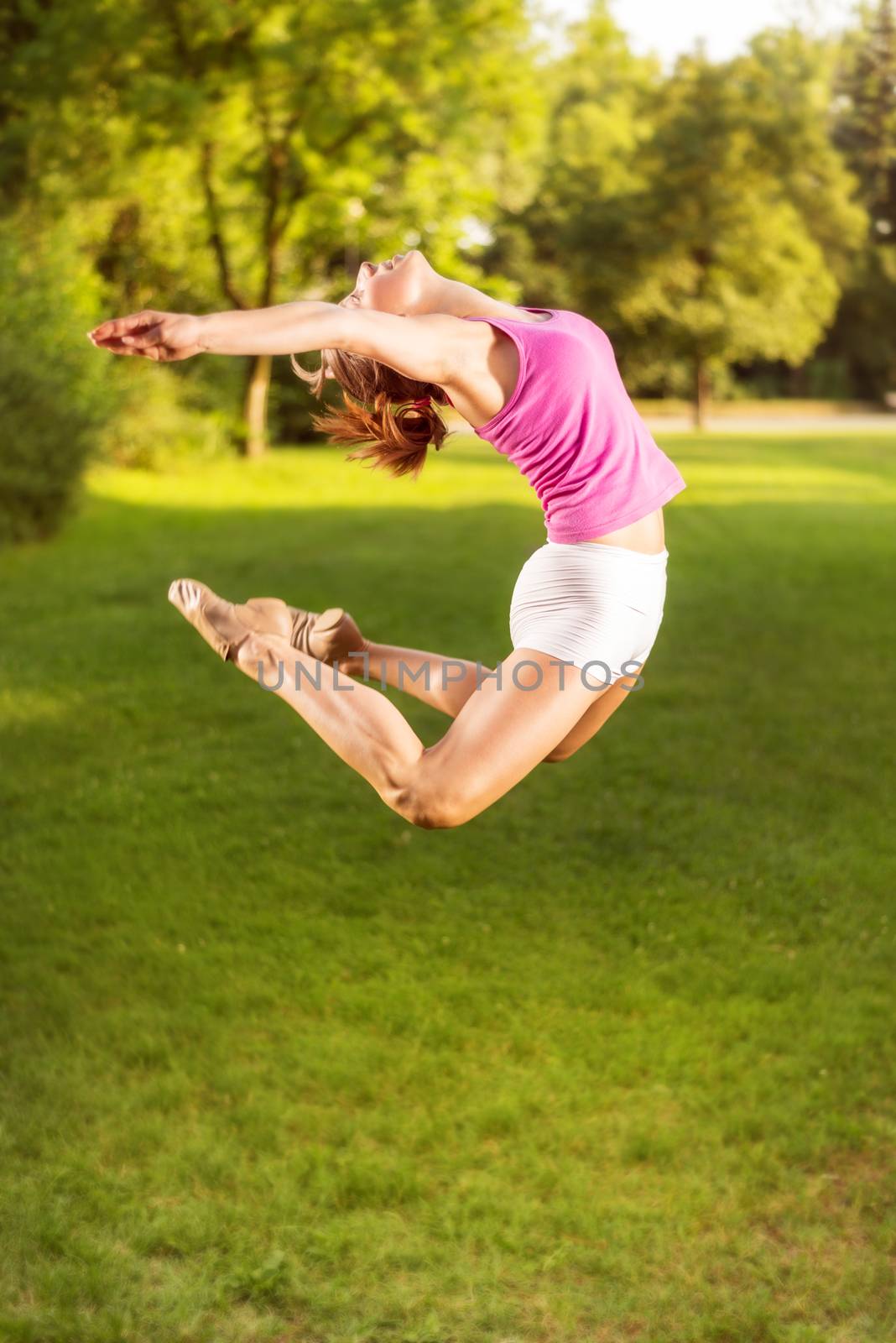 Cute sporty young woman jumping in the park.