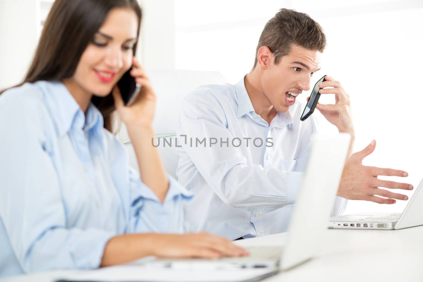 Young beautiful businessman in the office yelling on someone from other side of telephone.