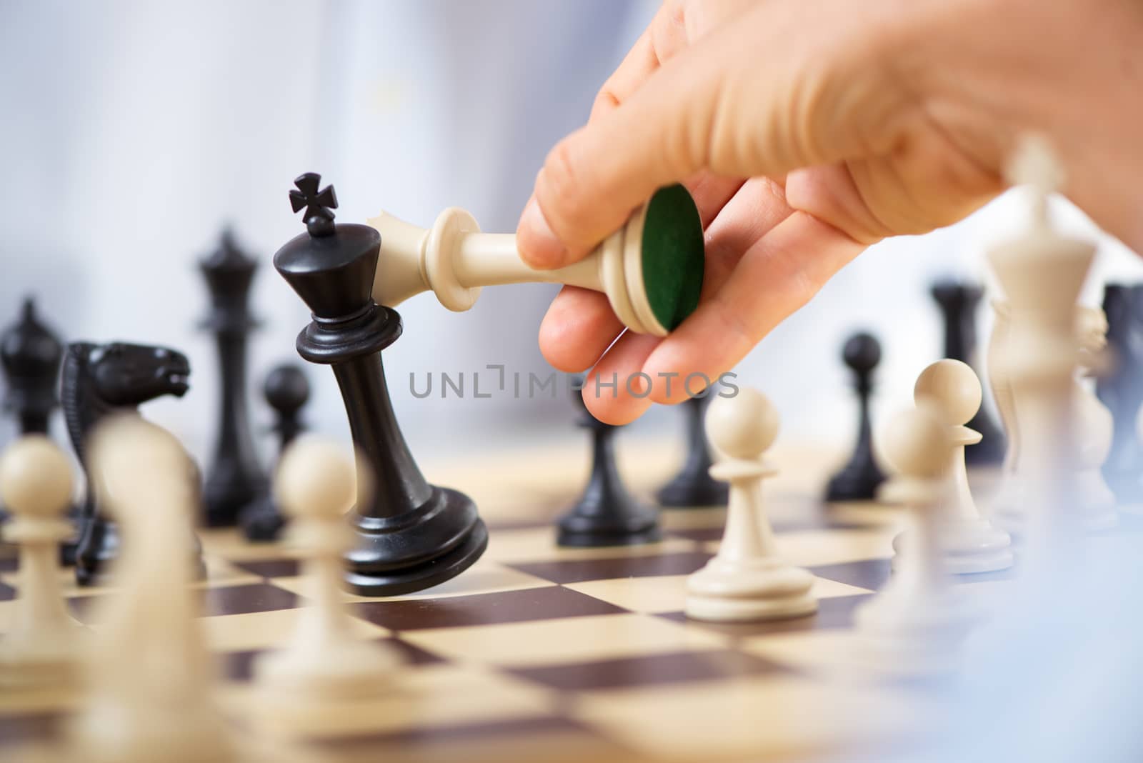 Man hand holding queen and king in checkmate position.