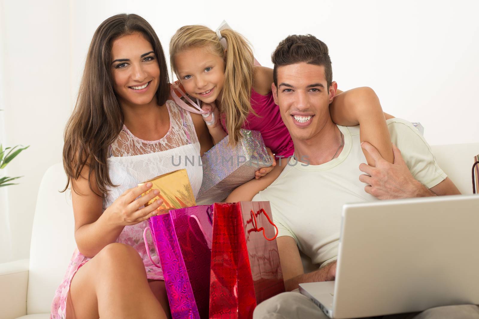 Beautiful happy family sitting at home with laptop and shopping bags.