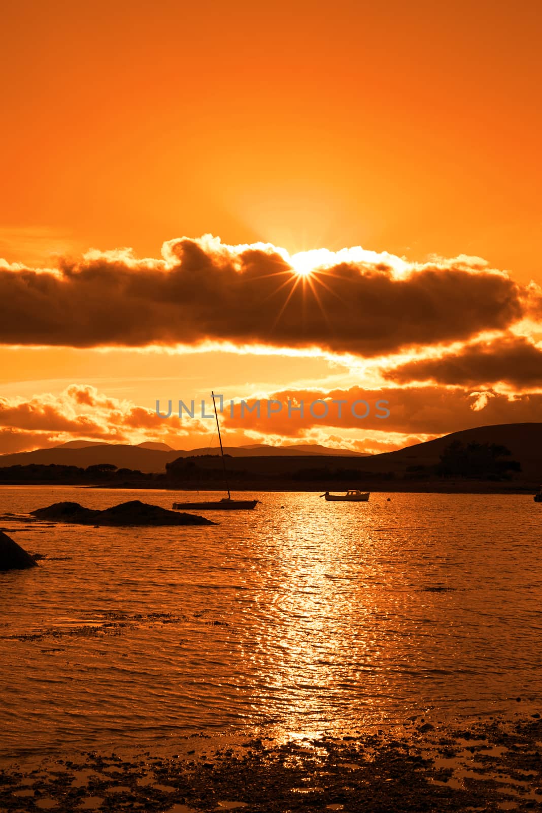boats in a quiet bay near kenmare on the wild atlantic way ireland with an orange sunset