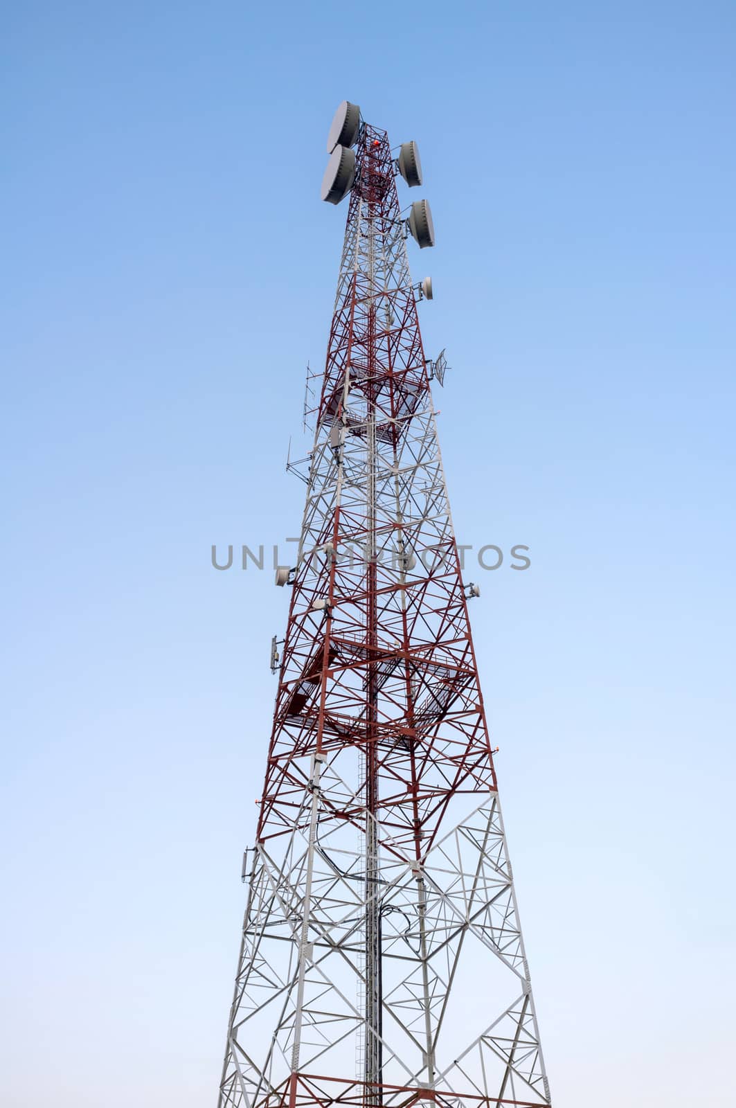 Telecommunications tower with clear blue sky.