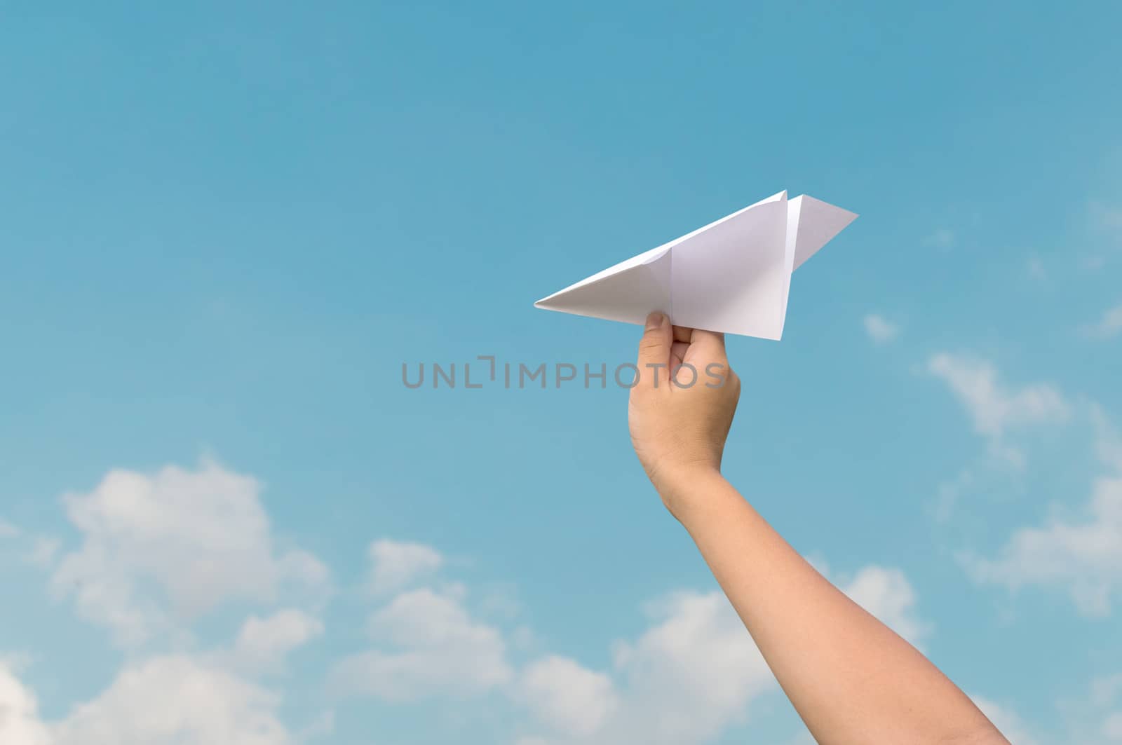 plane paper in children hand and blue sky in cloudy day