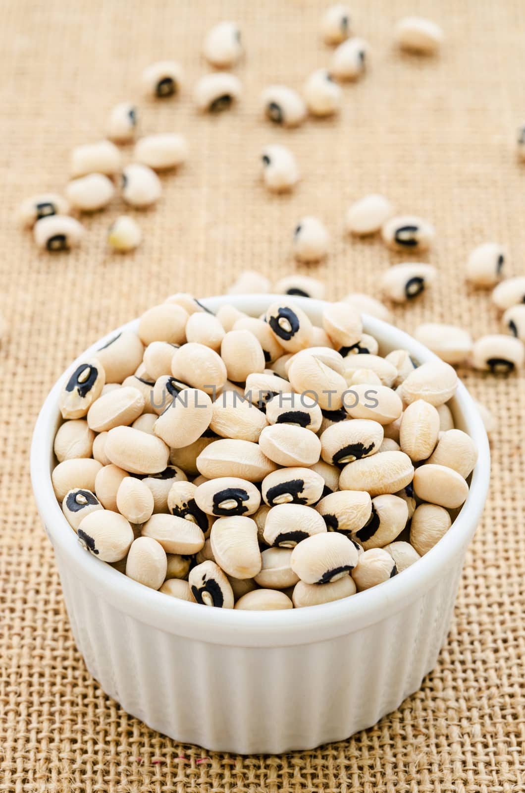 White bowl full of black-eyed peas on sack background.