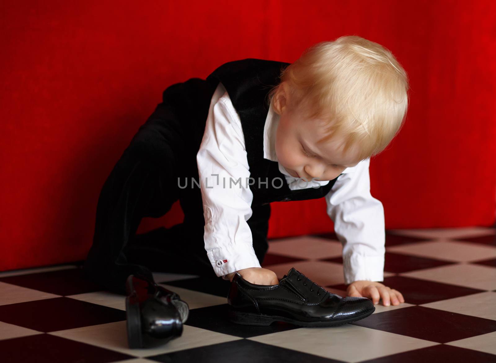 Little baby boy trying to wear patent leather shoes