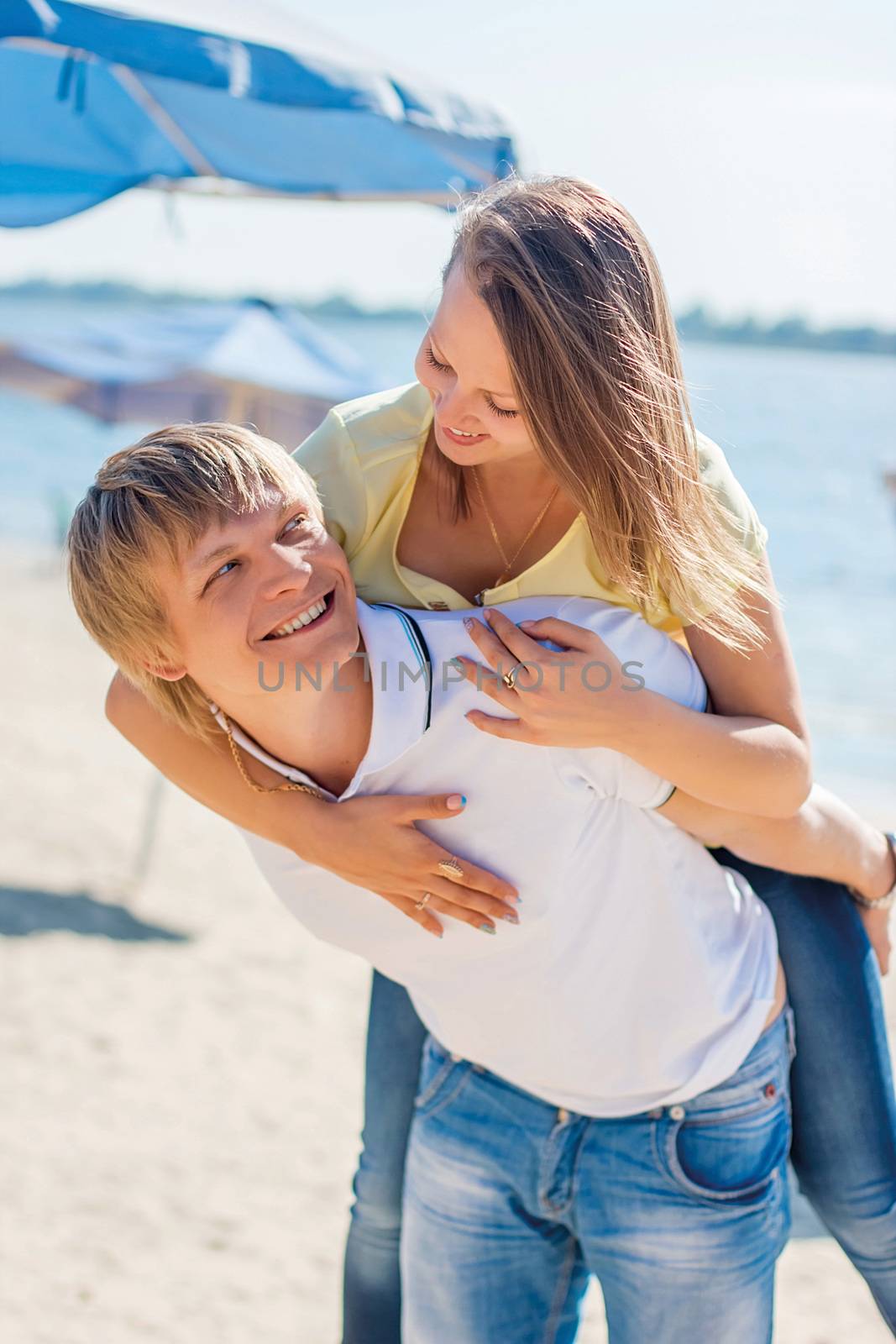 Young couple in love having fun and jumping on the beach. Positive emotions