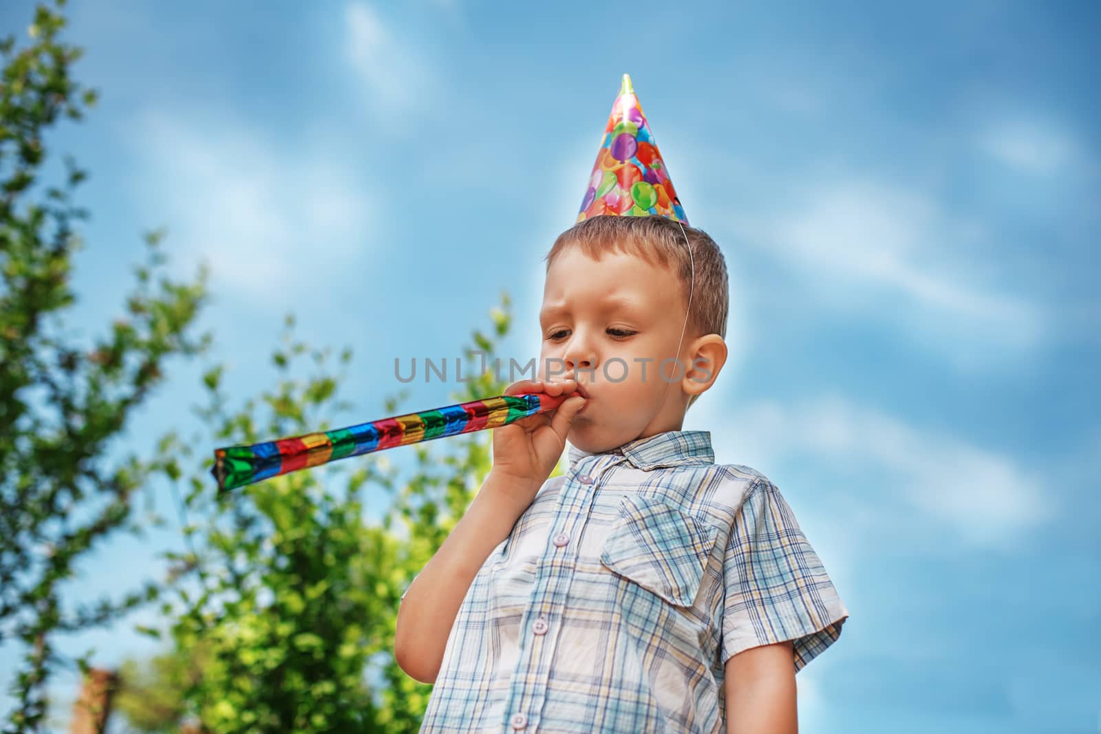 Little boy having fun and blows a party horn