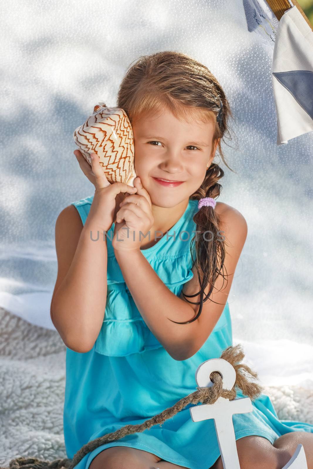 beautiful little girl listens to the sea through the shell