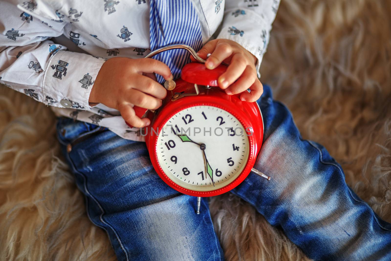 A little boy holding a big red clock waiting for miracles. Time concept