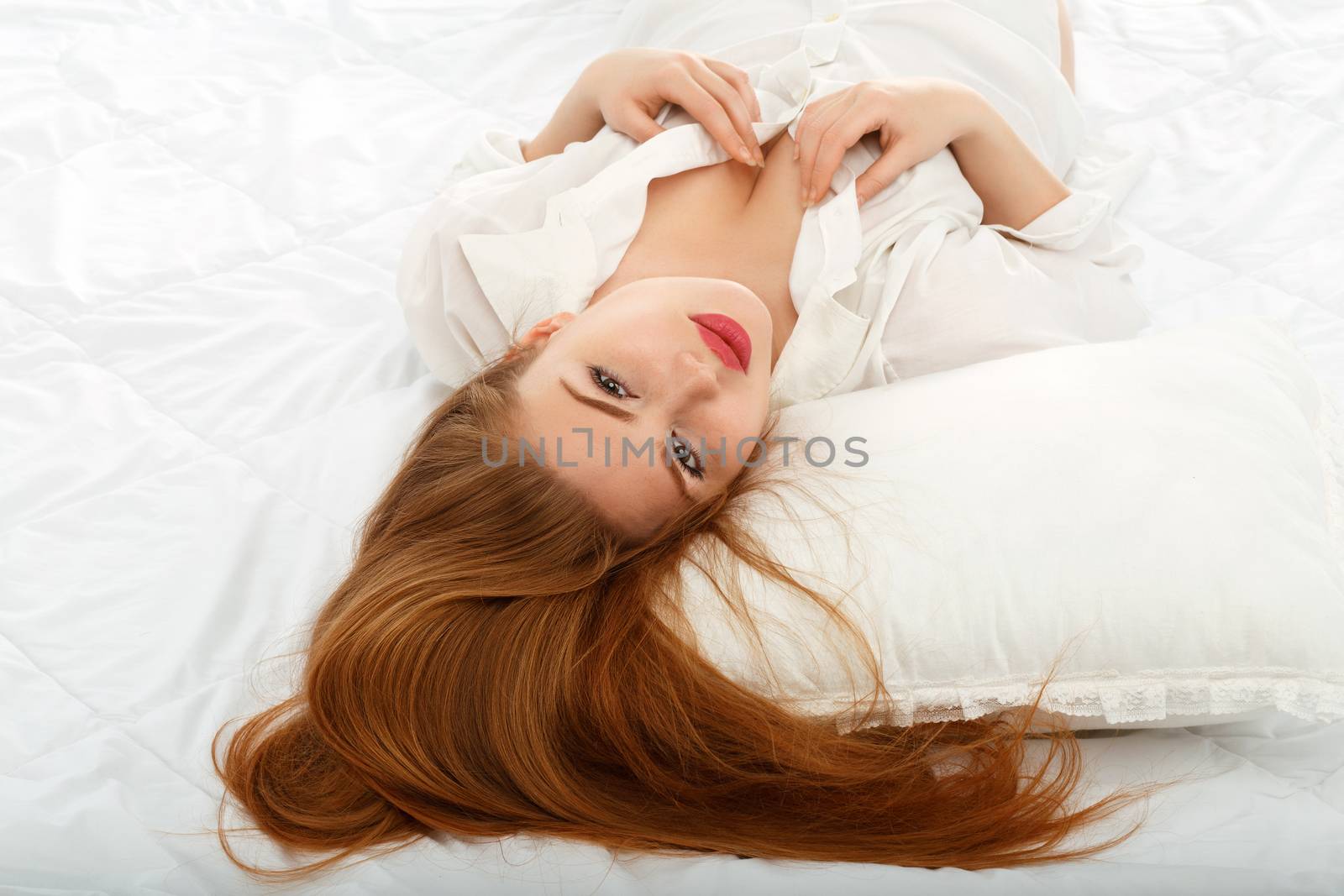 Portrait of a beautiful sexy girl lying on the back in bed in a man's shirt