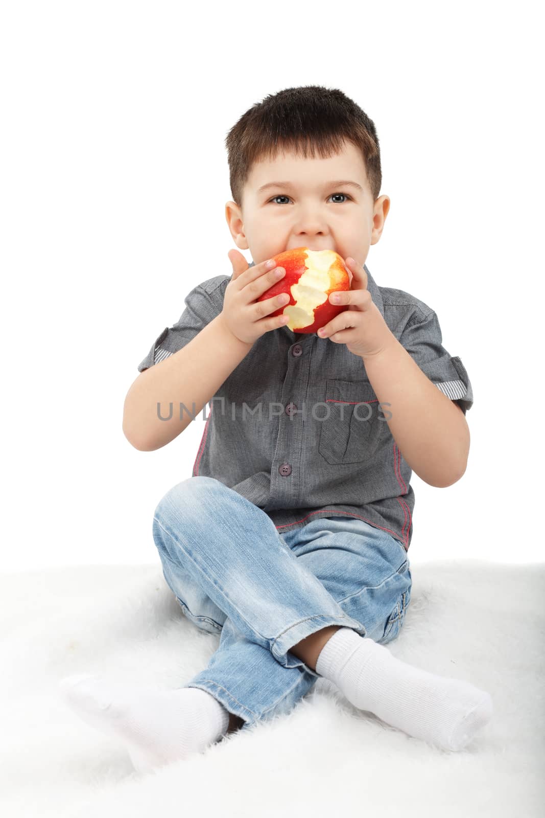 Little boy eating a red apple isolated on white background