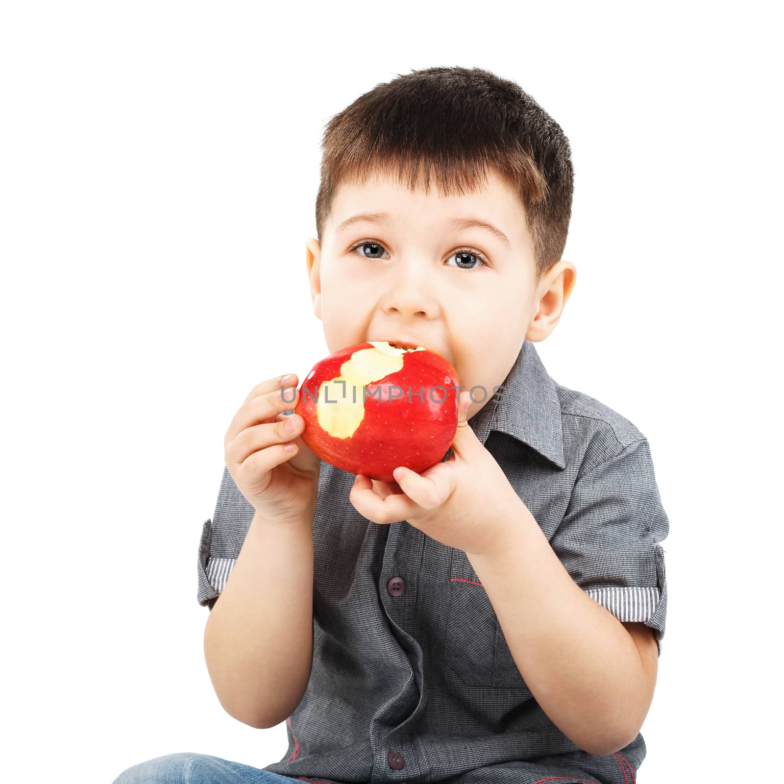 Close-up portrait of a little boy eating red apple isolated on white background