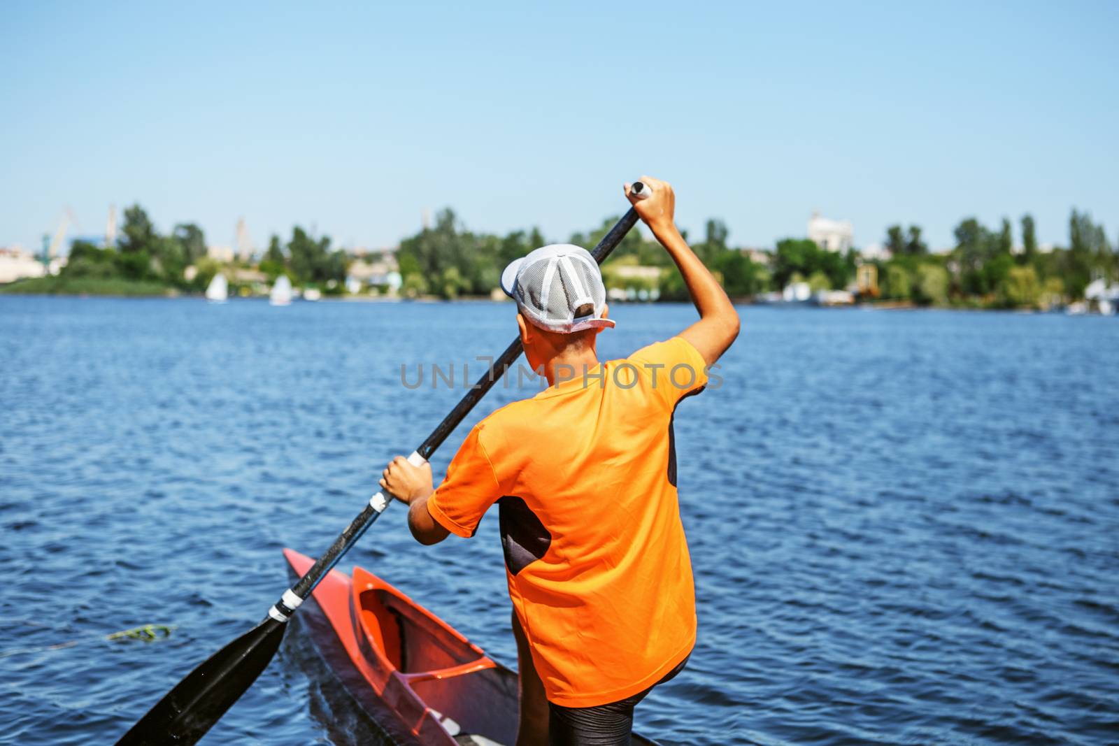 The boy rowing in a canoe on the river. Back view.