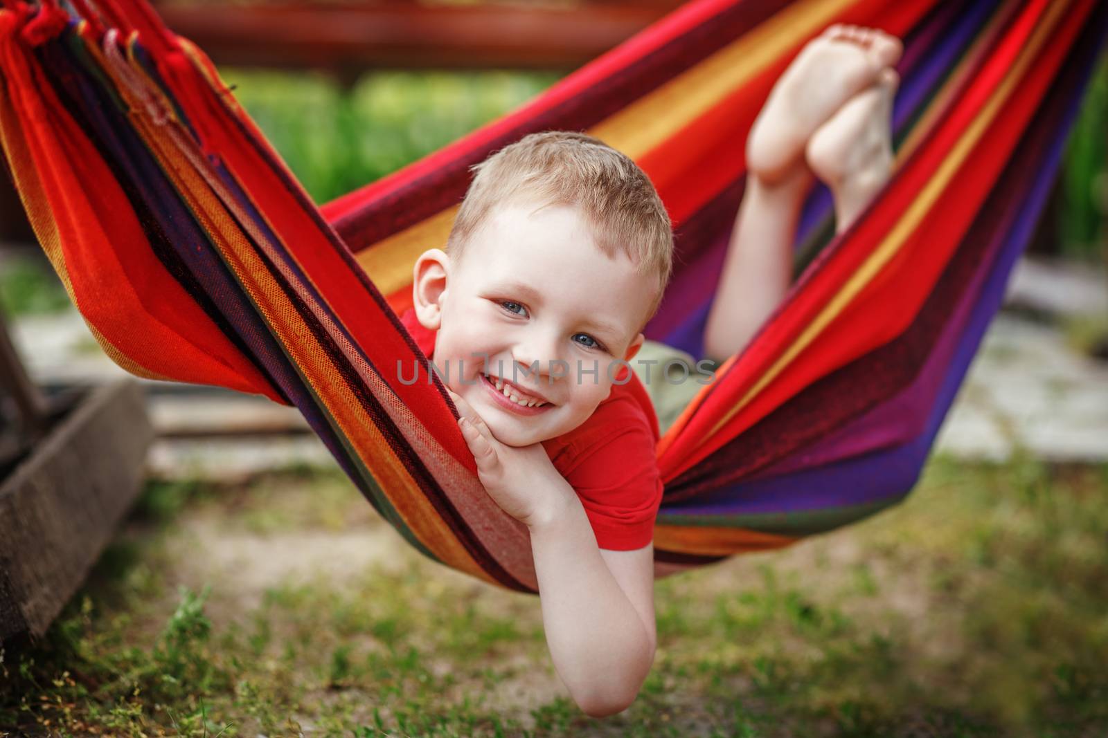 Beautiful cheerful little boy resting in a hammock and having fun. Positive emotions.