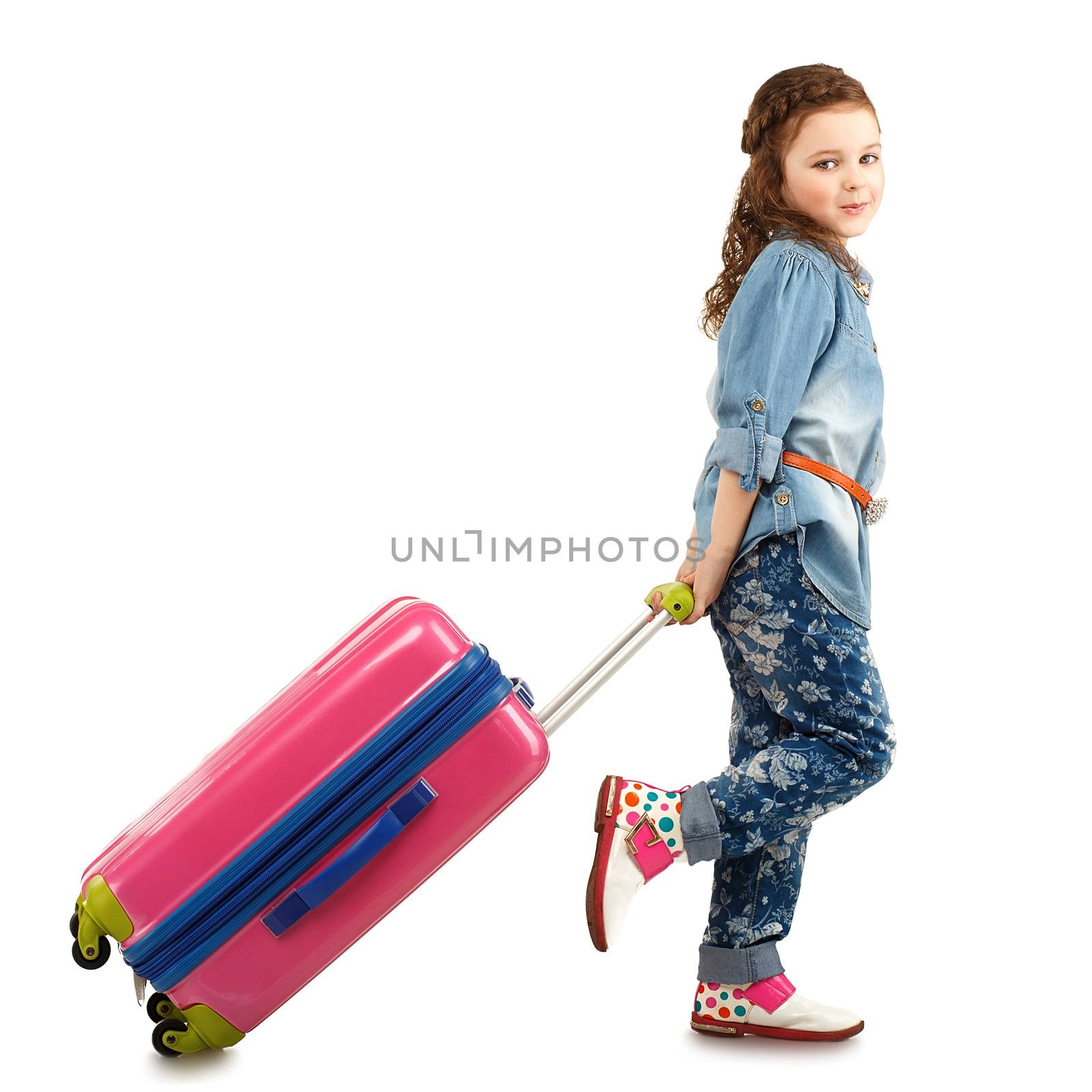 Full-length portrait of a pretty little girl with big pink suitcase on wheels isolated on white background. Concept holidays and vacations.