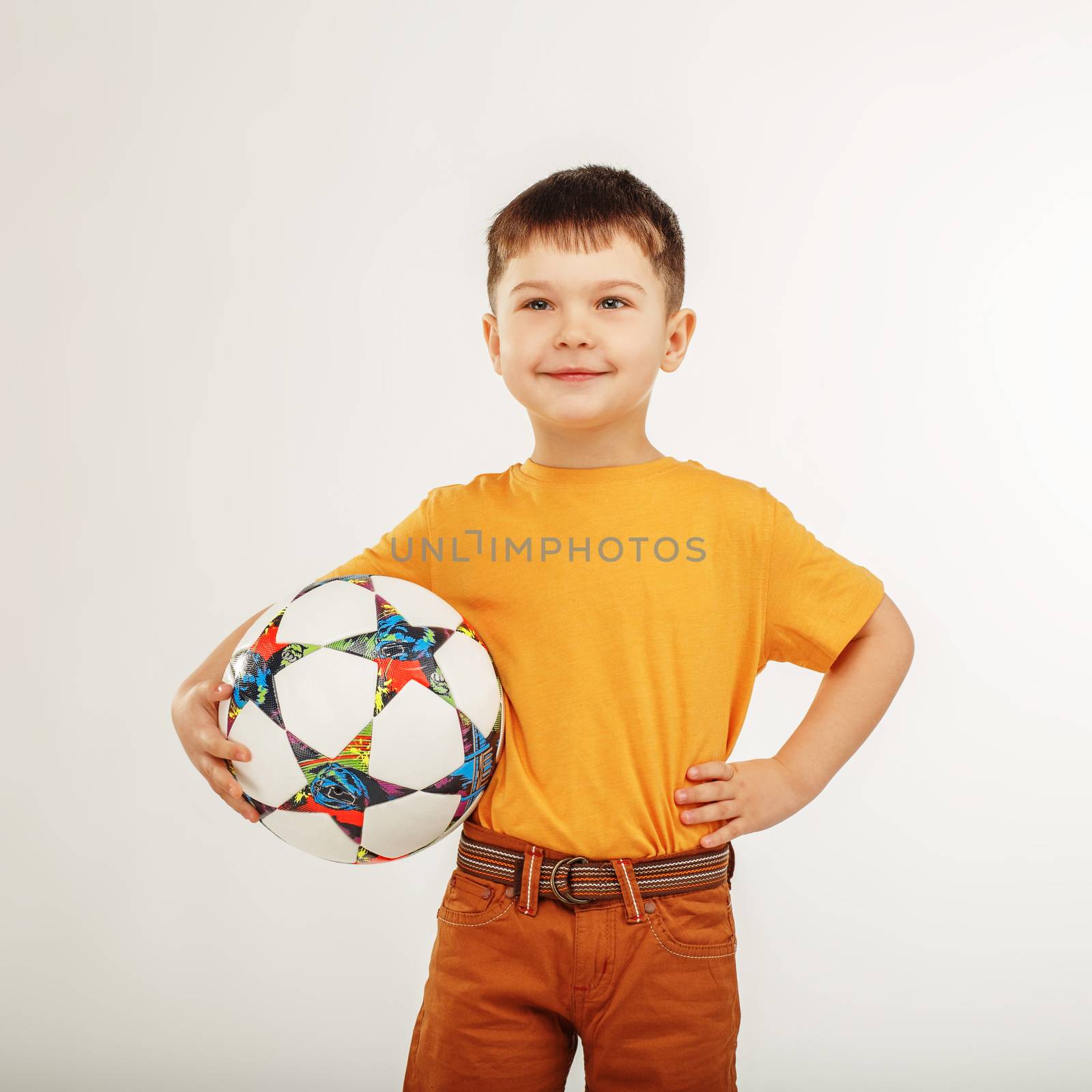 little boy holding a soccer ball under his arm by natazhekova