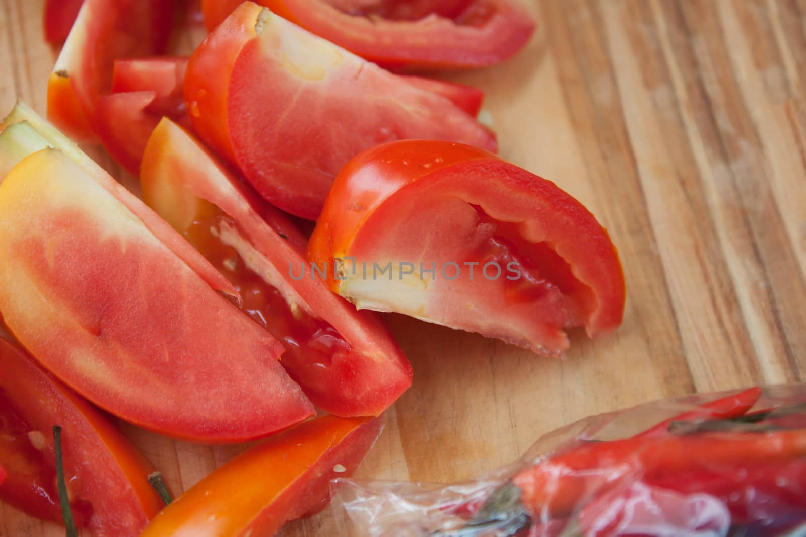 Tomatoes and peppers for cooking on a wood block.