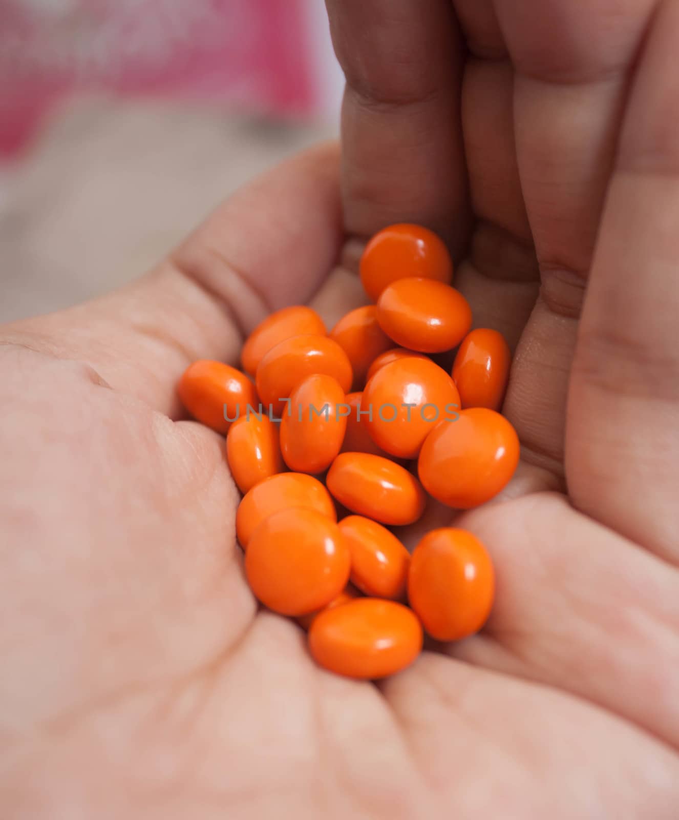 Orange pills closeup on hands.