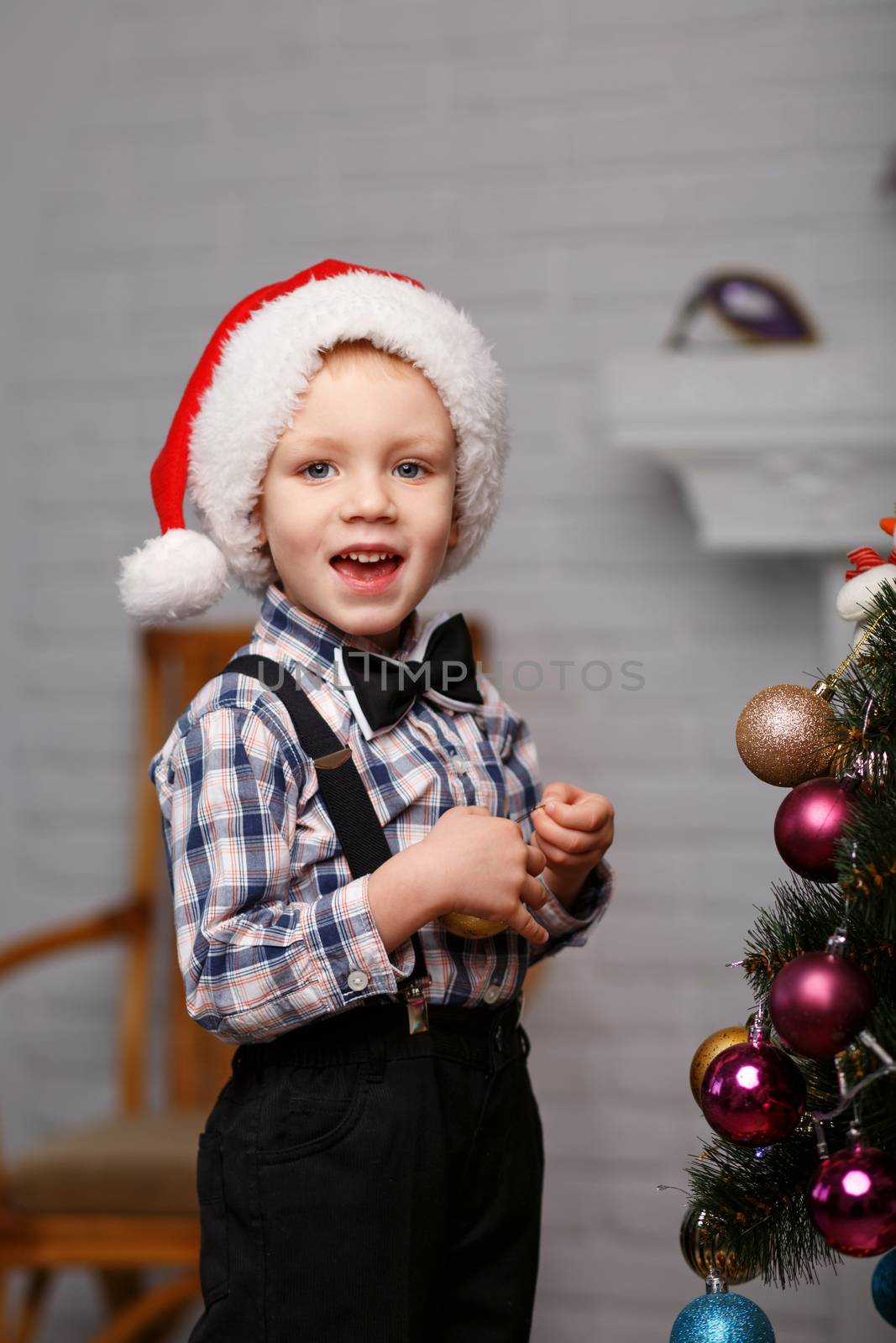 Cute little boy decorates a Christmas tree in the interior with Christmas decorations