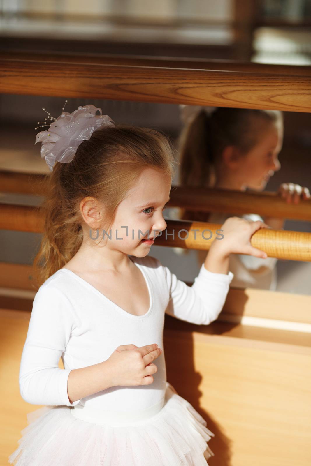 Ballerina little girl standing near mirror in the gym