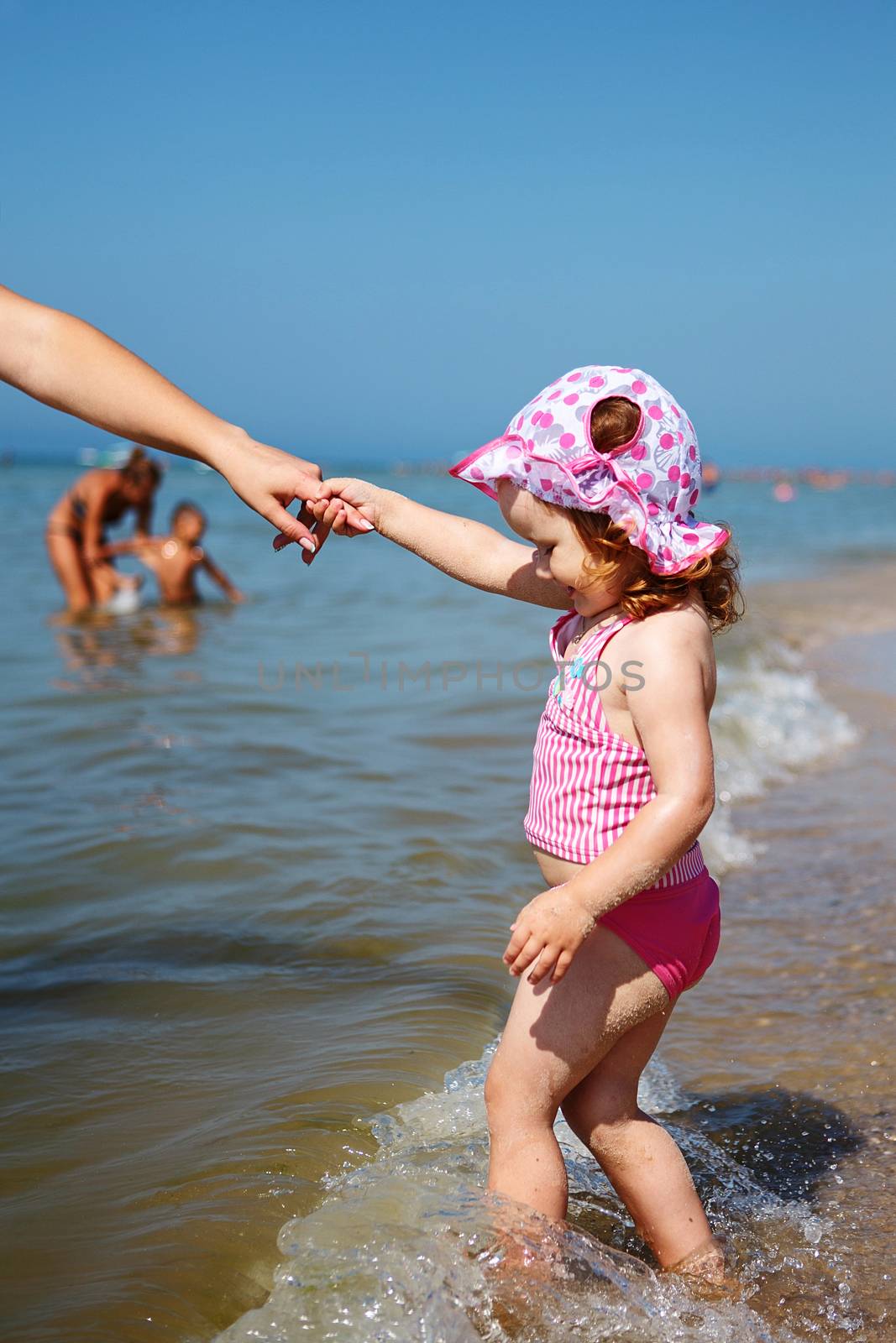 Cute little girl goes to swim holding the hand of his mother