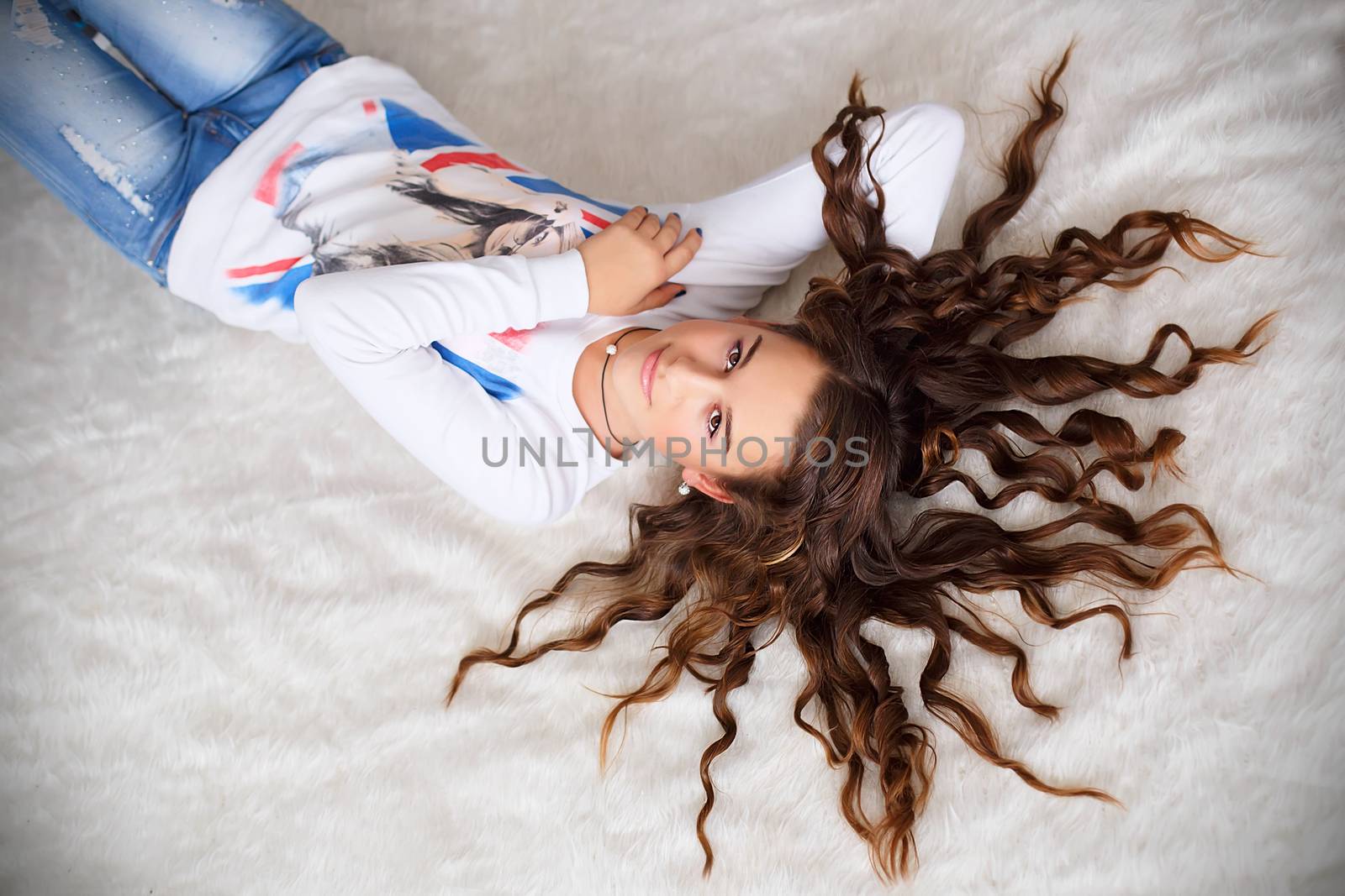 Portrait of a pretty teen girl lying on the floor with her long hair wavy