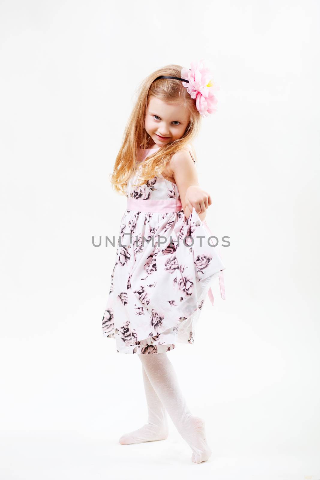 Full length portrait of a cute little blonde girl dancing against white background