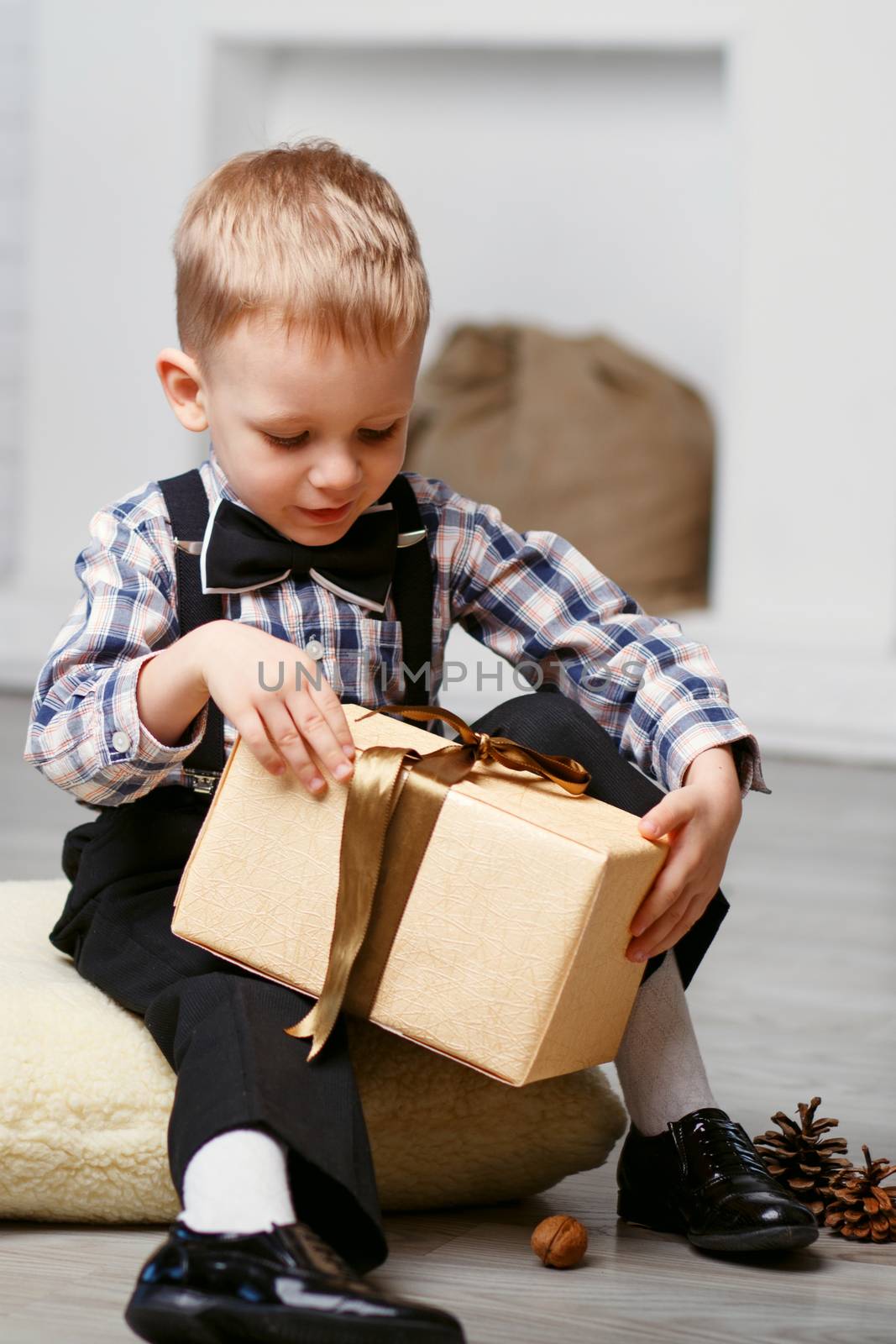 Smart Little boy opening a gift in Christmas decorations waiting for a miracle