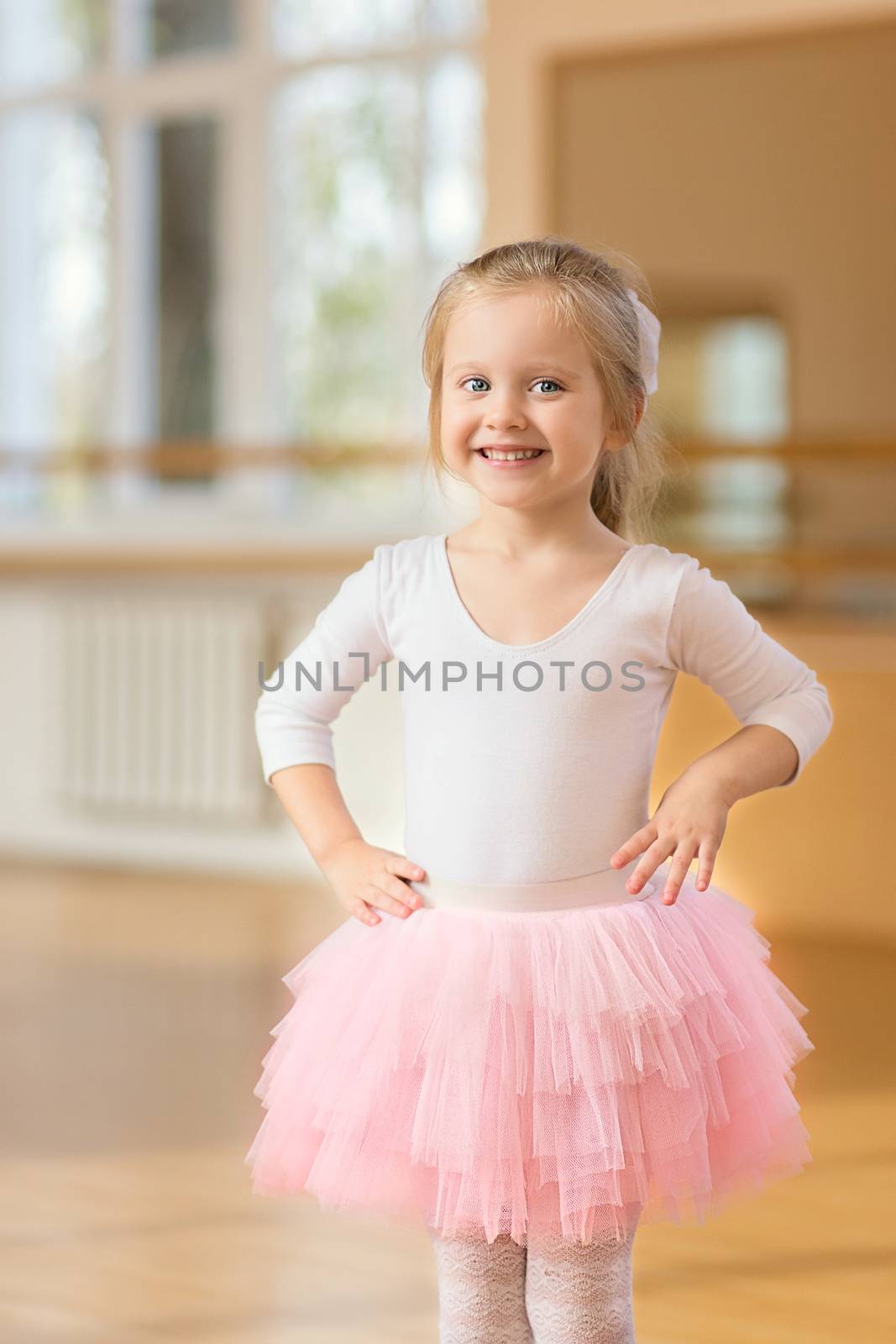 Ballerina little girl standing near mirror in the gym