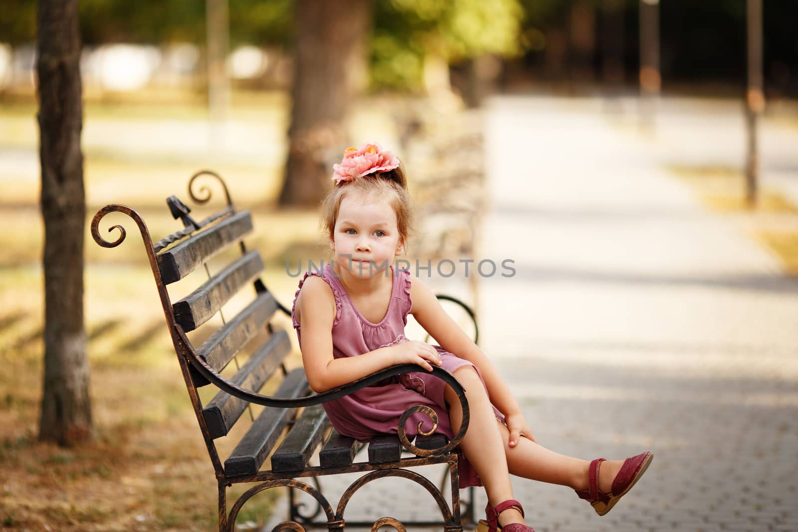 Portrait of a smiling pretty little girl sitting on a park bench