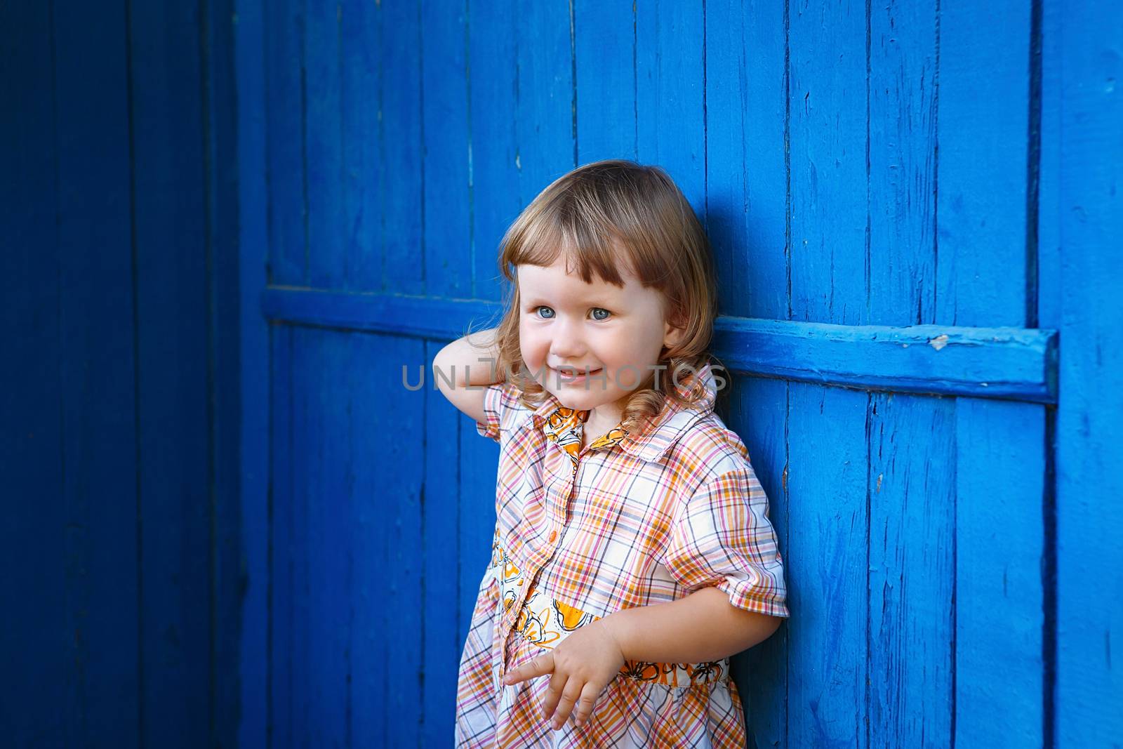 Portrait of happy joyful beautiful little girl against the old textured blue wall