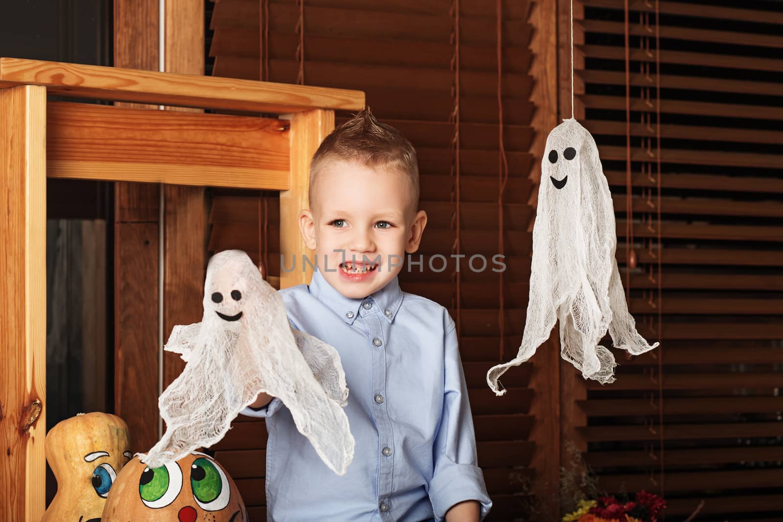 Cute Little Boy having fun in Halloween decorations. Halloween party with child holding toy ghost