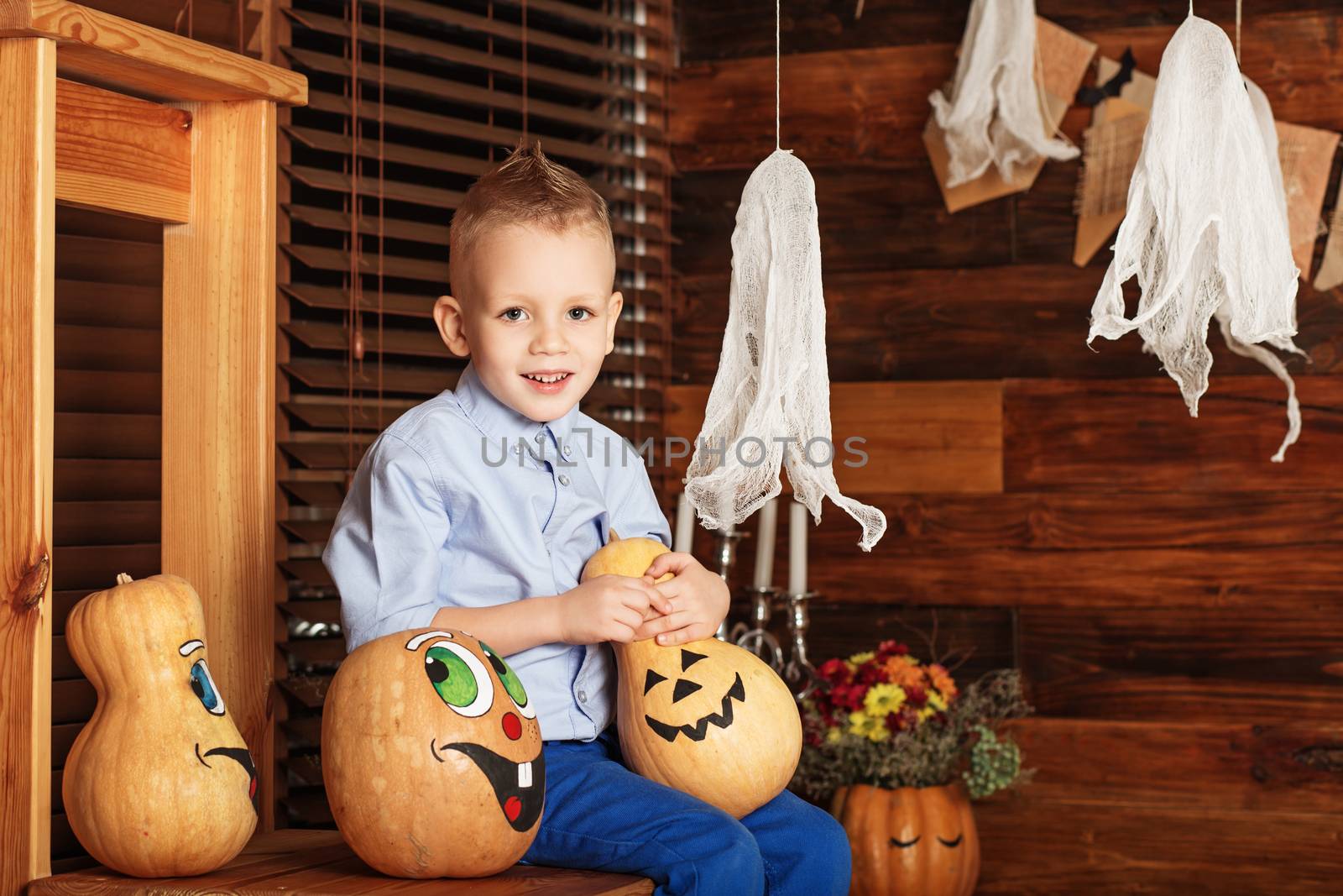 Halloween party with child holding painted pumpkin. Little Boy having fun in Halloween decorations