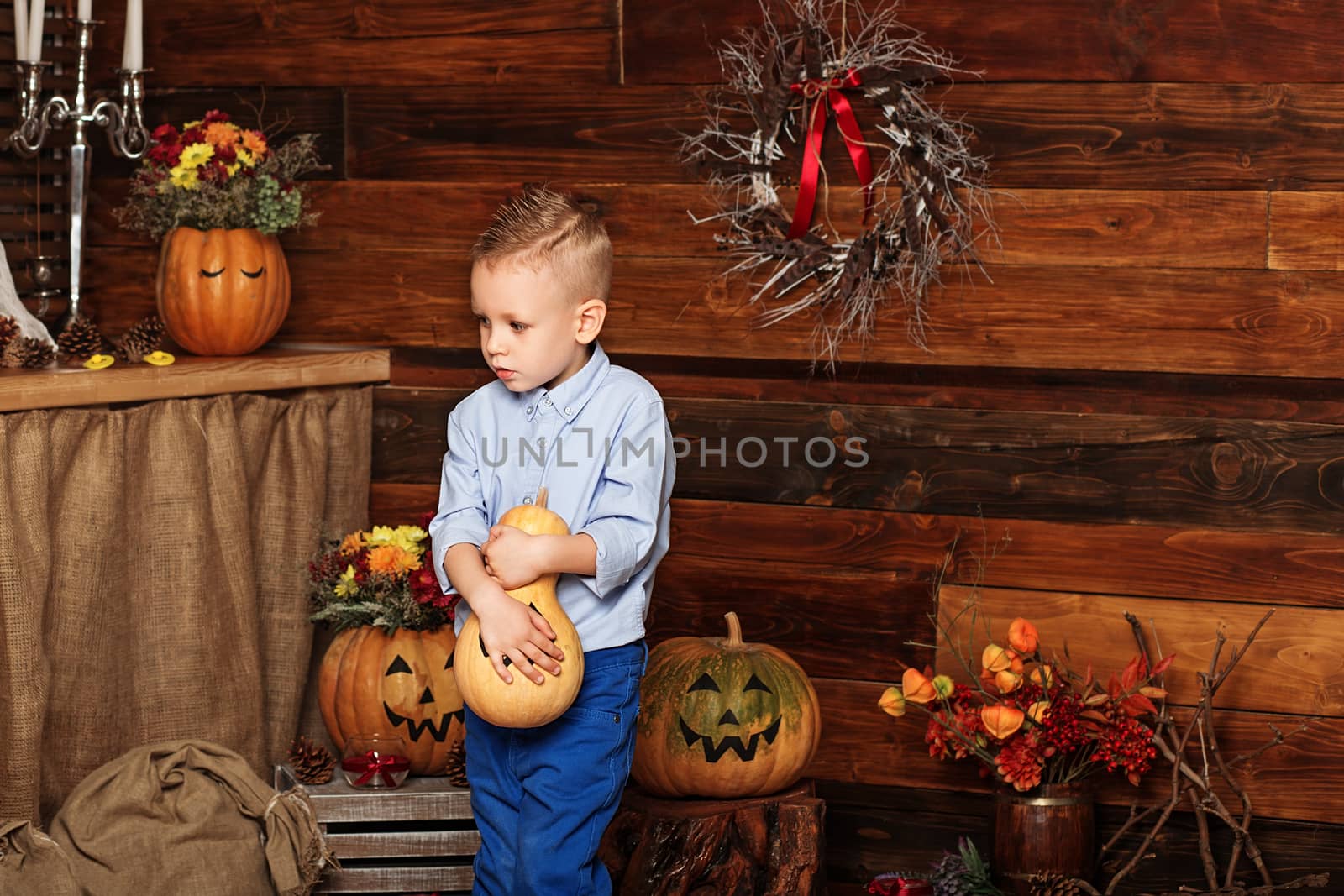 Cute Little Boy having fun in Halloween decorations. Halloween party with child holding painted pumpkin