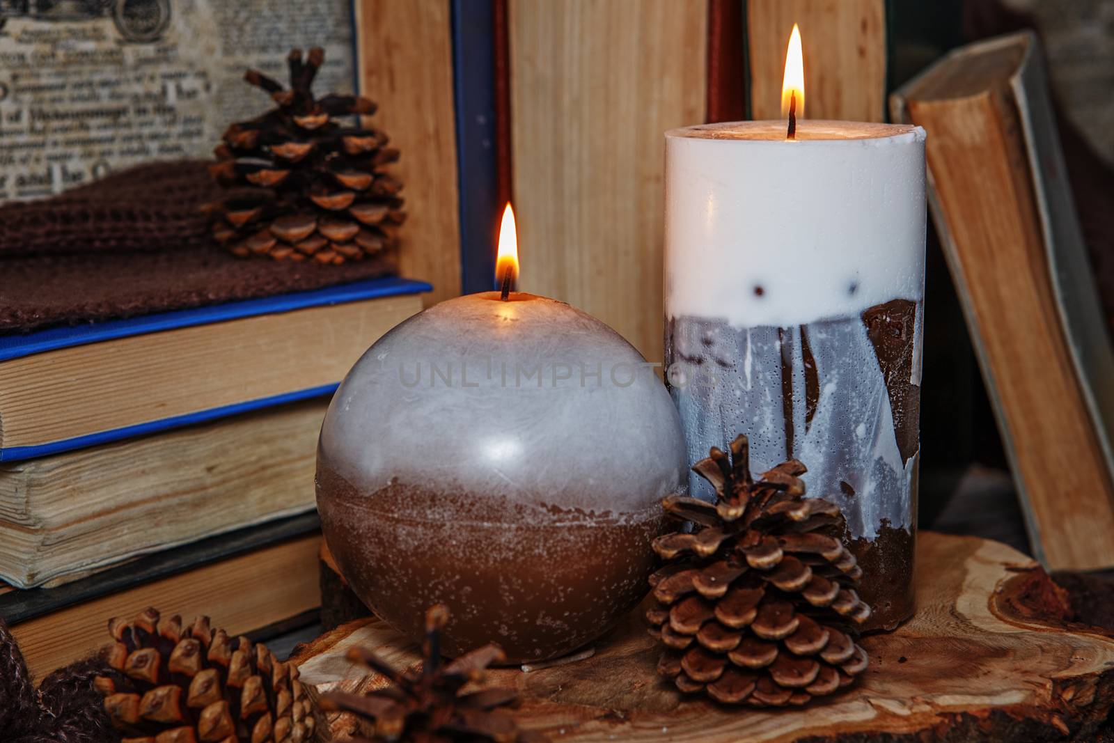 Decorative Handmade candles on openwork knitted white napkin among the old books. Handmade candles lit in vintage interior