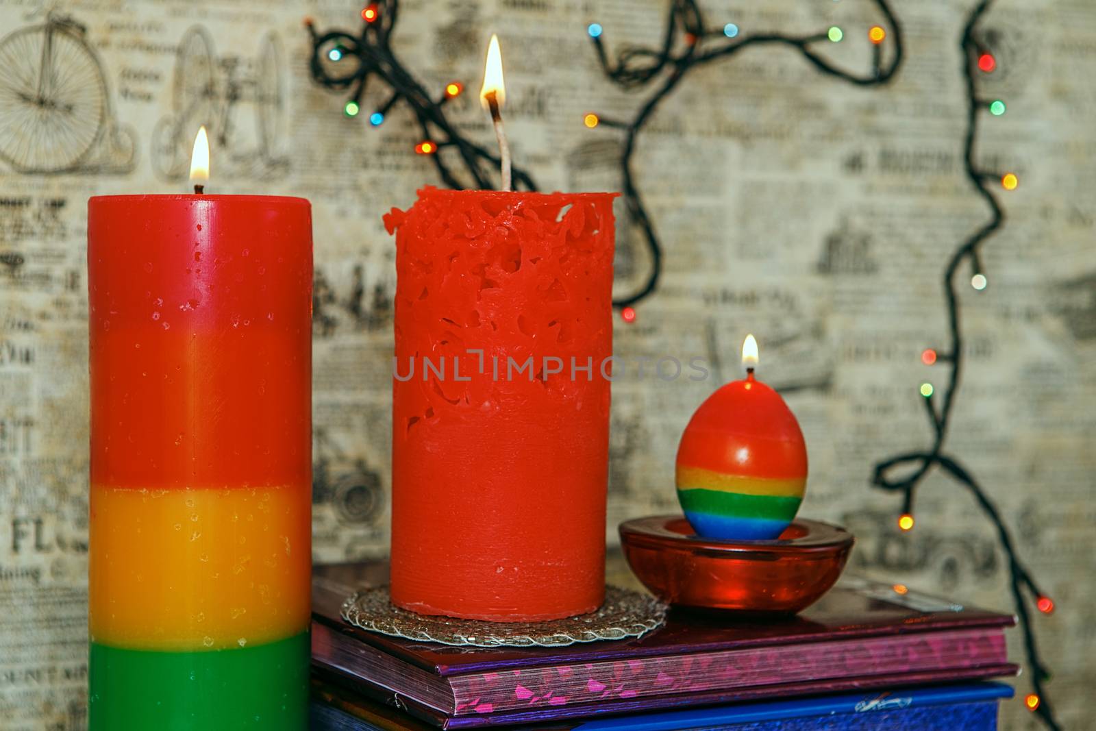 Composition of the three burning rhandmade candles among colorful books. Light the candles. A burning candle. Candle lit. Candle Light