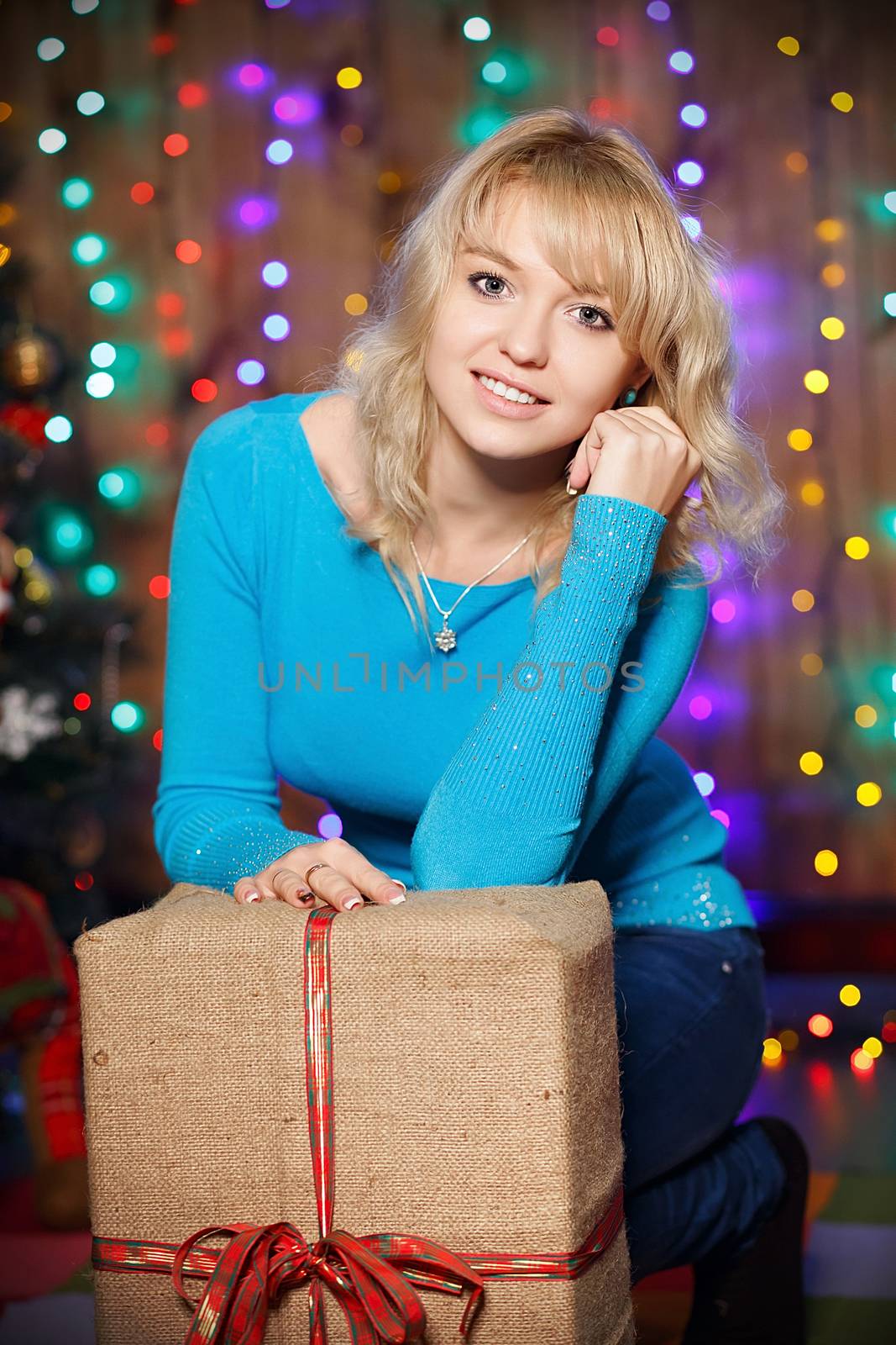 Portrait of attractive young female charming blonde with a great gift in the box interior with Christmas decorations