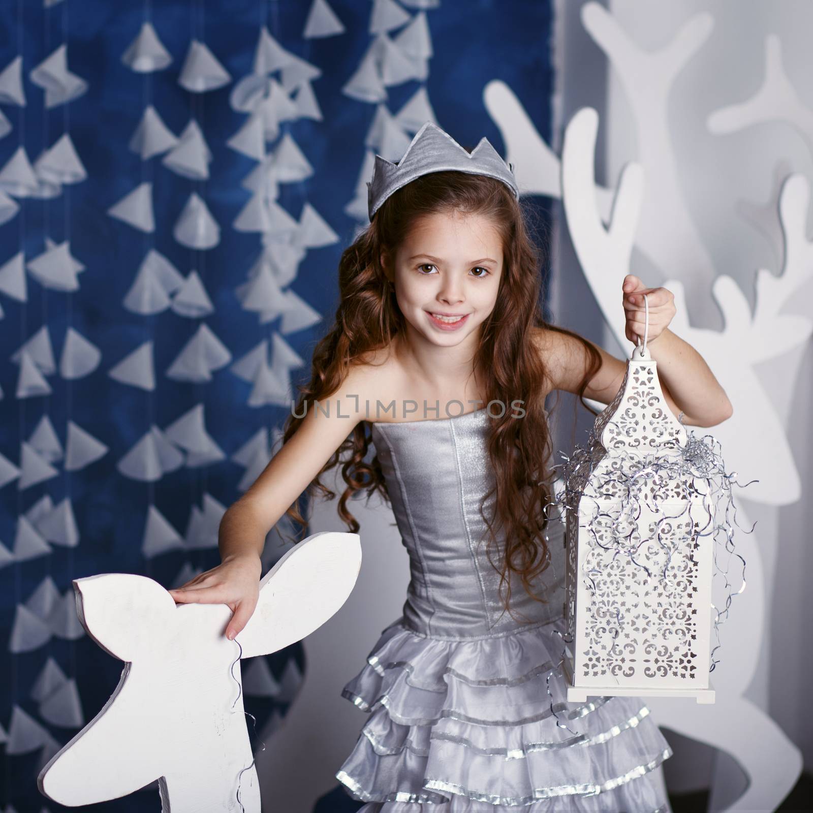 Little girl in christmas decorations. Portrait of Beautiful little girl with long curly hair with crown. Decor winter forest. Little Princess