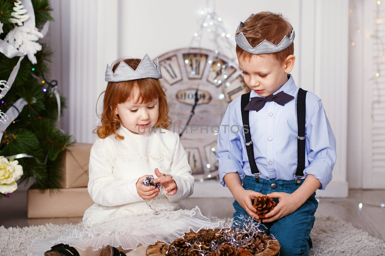 Two elegant little kids decorating Christmas tree with fir-cone. New year preparation. Happy children and family.