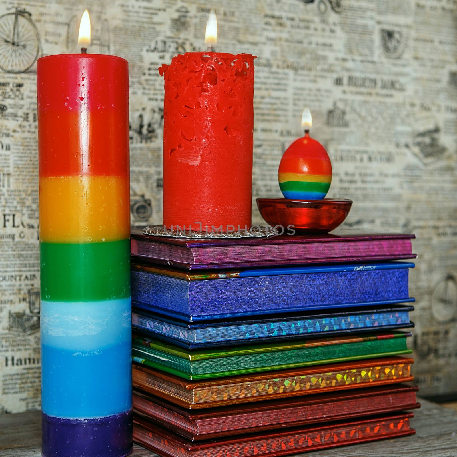 Composition of the three burning rhandmade candles among colorful books. Light the candles. A burning candle. Candle lit. Candle Light