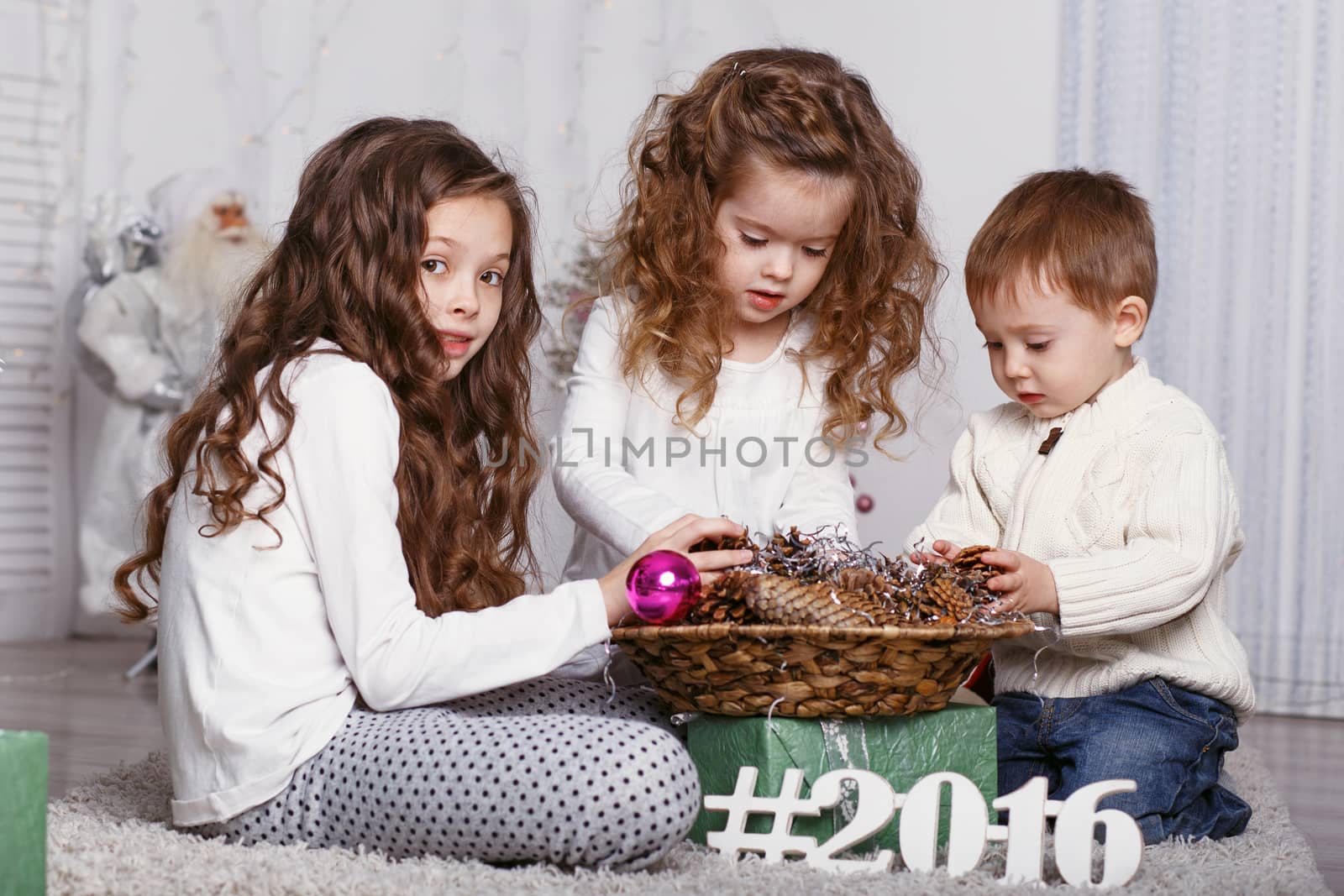 three little siblings decorating Christmas tree with fir-cone. by natazhekova